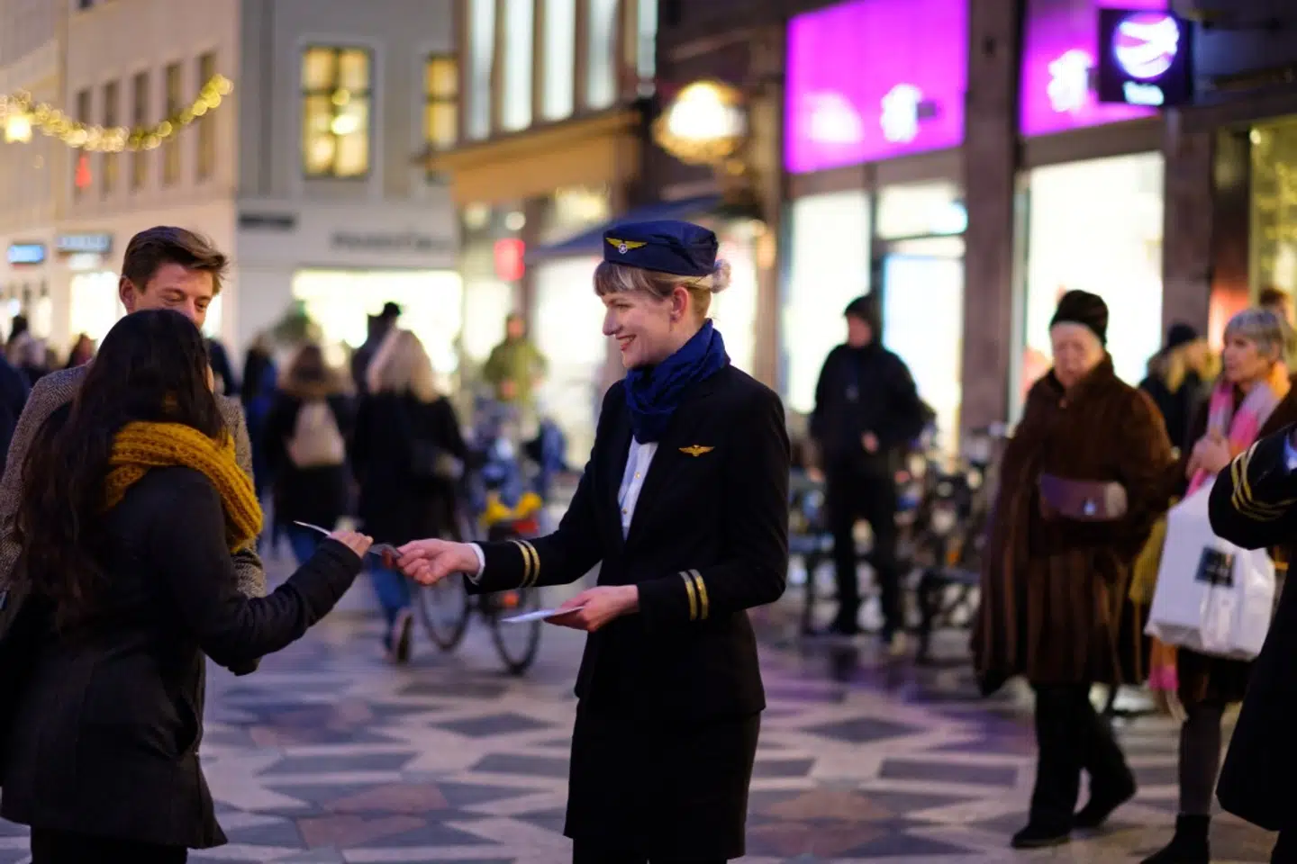 Aurelija Aniulyte ved aktion klædt ud som stewardesse og i gang med at dele boardingpasses ud til folk