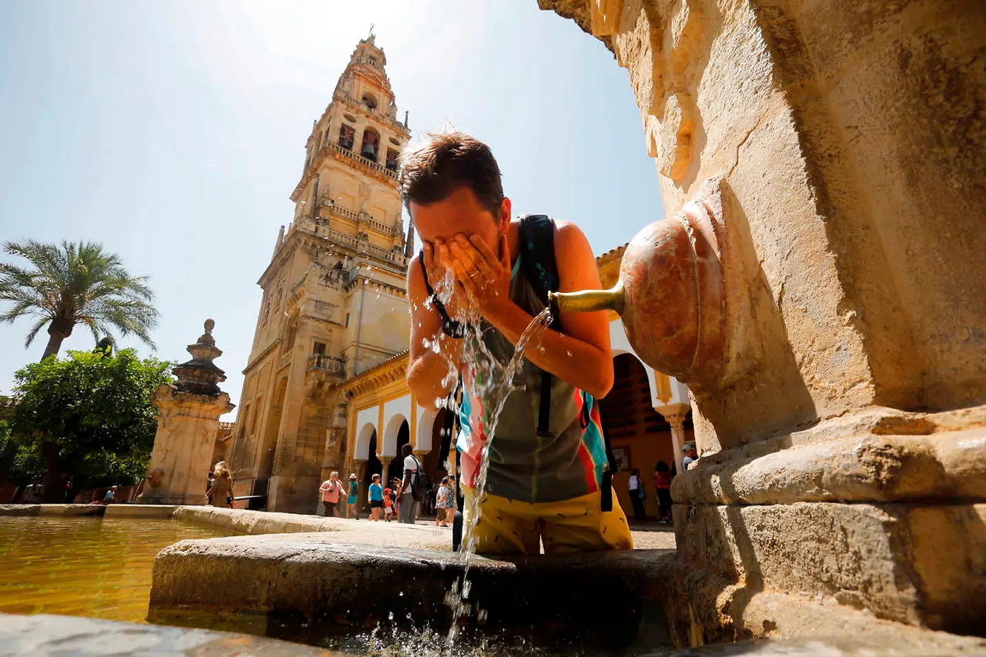 En turist snupper en tår vand fra en vandpost i den spanske by Cordoba.