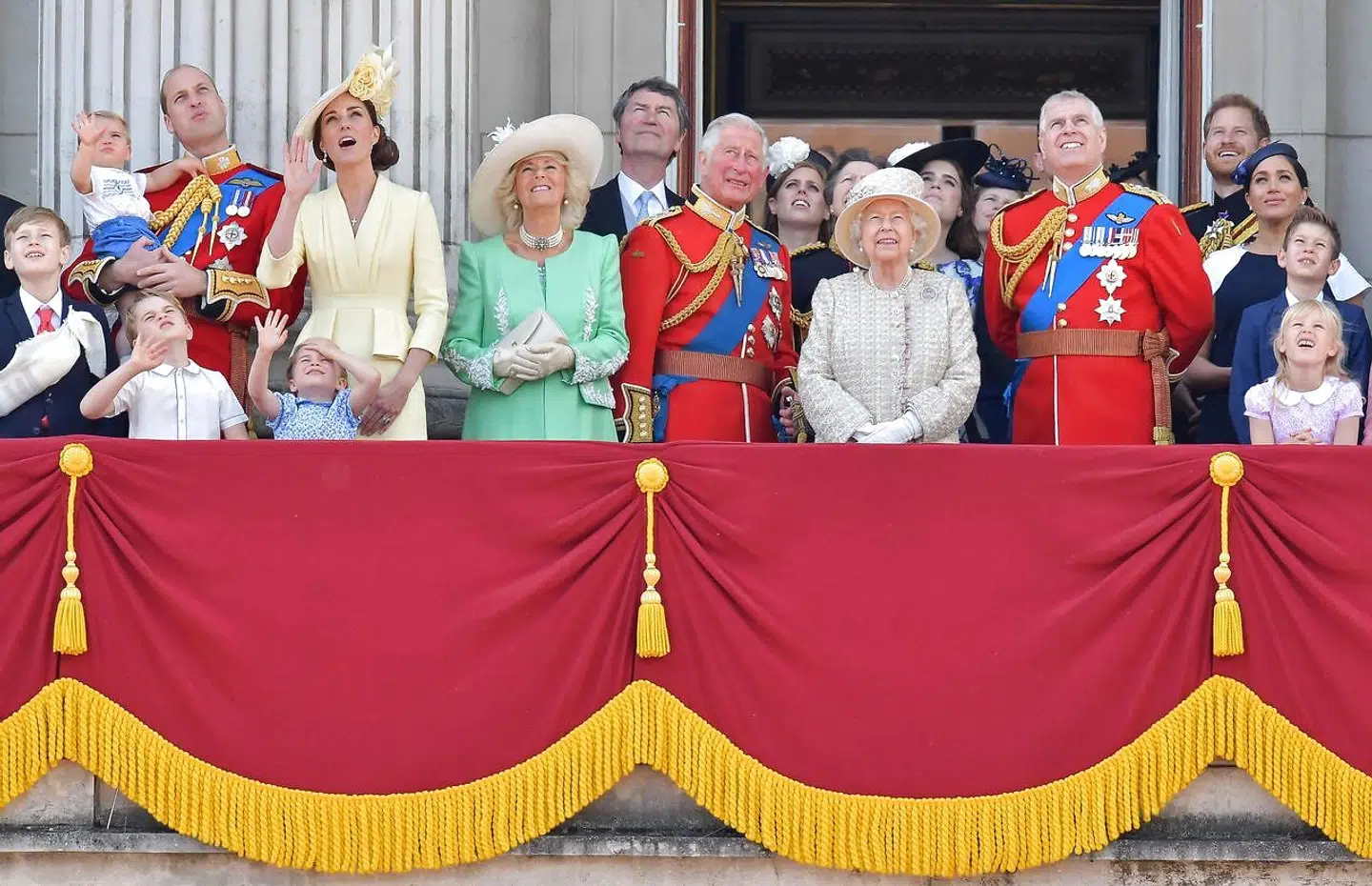 Her ses prins William med prins Louis i favnen, hertuginde Kate, prinsesse Charlotte, prins George, hertuginde Camilla, prins Charles, dronning Elizabeth, prins Harry og hertuginde Meghan på balkonen sammen med andre medlemmer af den kongelige familie.