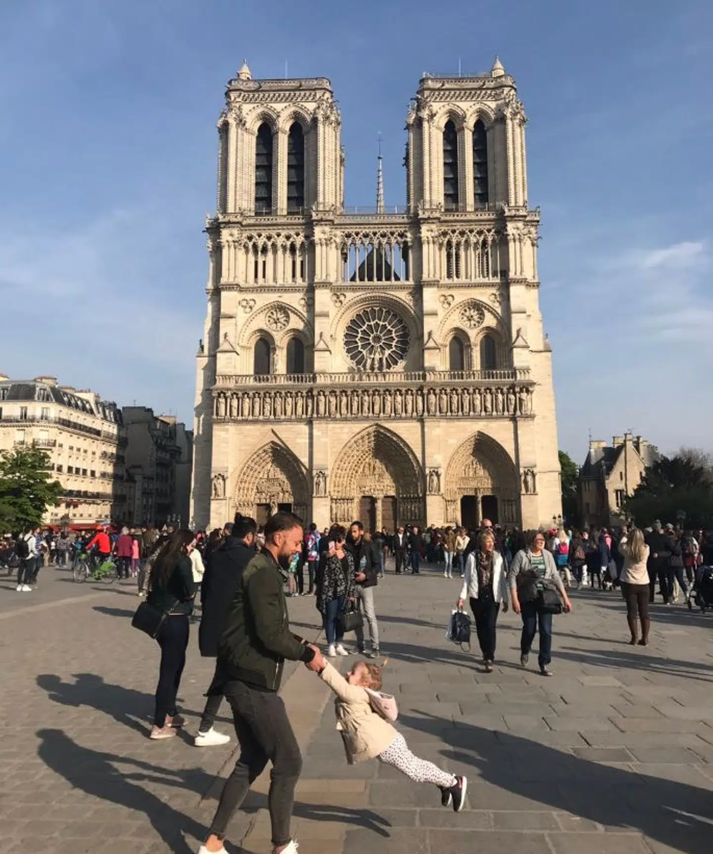 Dette billede gik verden rundt, efter at den ikoniske katedral Notre Dame brød i brand. Nu har fotografen fået kontakt til faren, der leger med sin datter på billedet. Det blev taget, blot en time før katedralen begyndte at brænde.