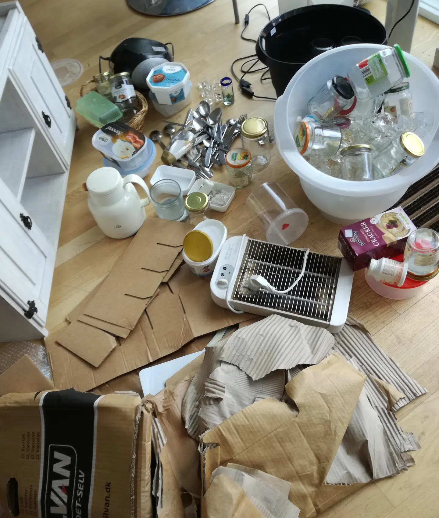 Defekt elektronik, syltetøjsglas og gamle plastikbøtter fra is efterladt i gennemblødte papkasser foran en genbrugsbutik fra Danmission.