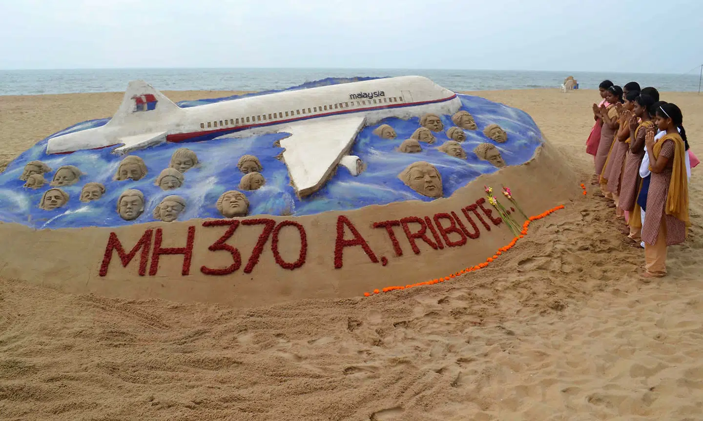 Skolepiger beder ud for en sandskulptur skabt af den indiske sandkunstner Sudarshan Patnaik for at hylde passagererne og besætningen ombord på Malaysia Airlines-flyvning MH370 på en strand i Puri i den østlige indiske delstat Odisha den 25. marts 2014.