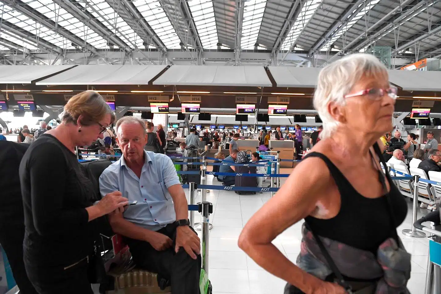 Passagerer venter ved check-in skranken i Suvarnabhumi International Airport i Bangkok. Flere hundrede er standede inde i sele lufthavnen, mens lige så mange venter uden for.
