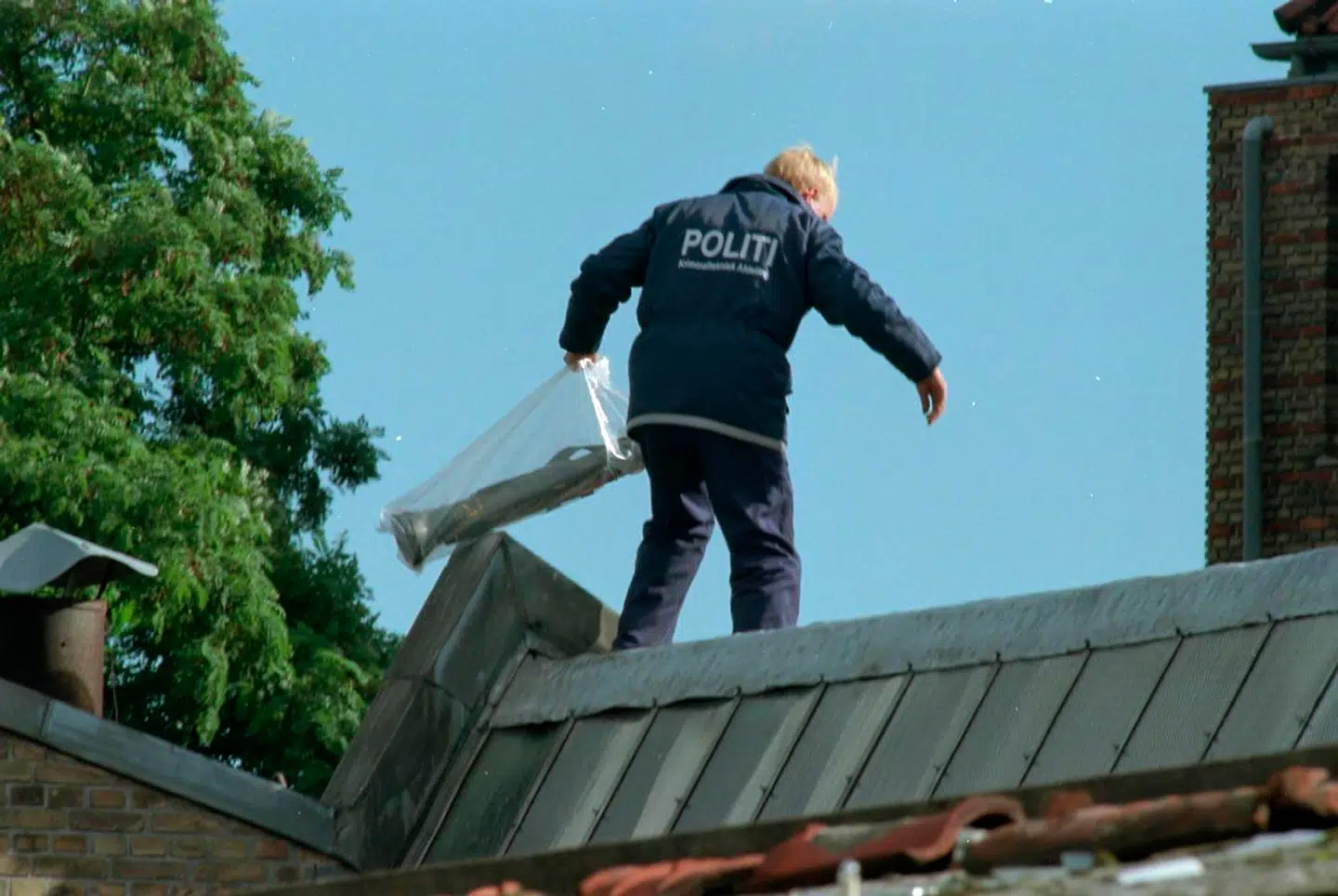 En politimand med en af de to panserværnsraketter, som blev fundet på et tag over for Hells Angels hus i Titangade. NORDFOTO 1996