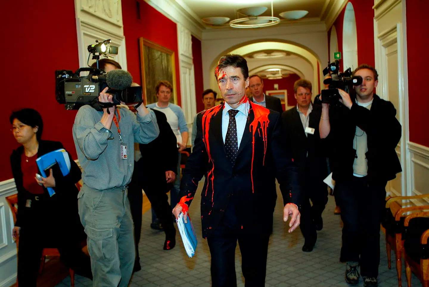 Statsminister Anders Fogh Rasmussen (V) blev 18. marts 2003 overfaldet af en aktivist fra Globale Rødder efter et møde i Folketingets Udenrigspolitiske Nævn. Her går han mod Statsministeriet overhældt med maling. B.T.s Andreas Karker følger efter som nr. 2 fra venstre.