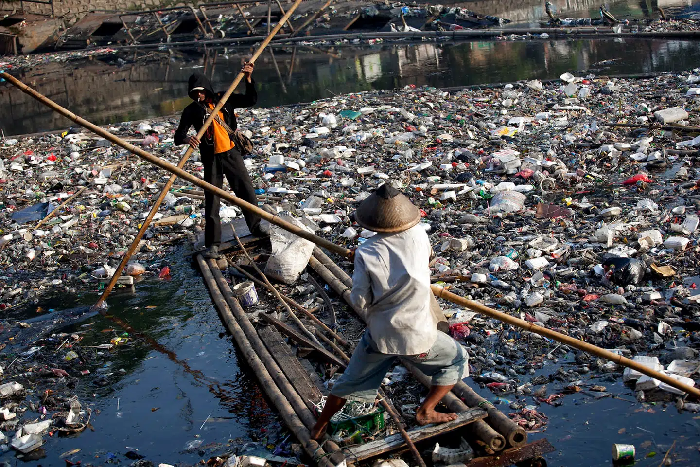 Sanitetsarbejdere på en pram arbejder med at samle affald op fra en flod i Jakarta.