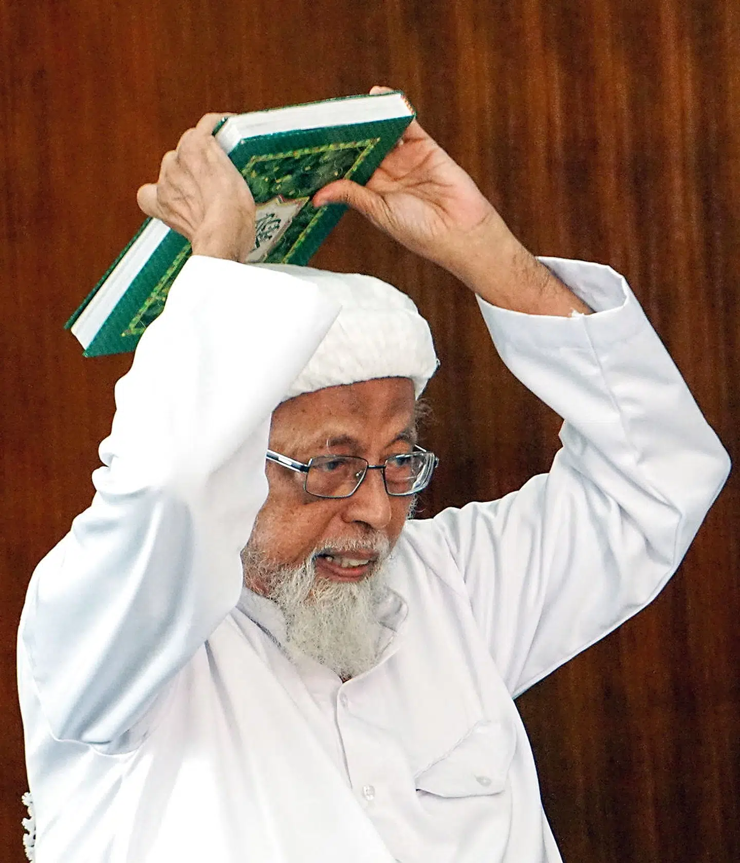 De indonesiske præst Abu Bakar Bashir holder Koranen over sit hovede, da han i 2016 var i retten.