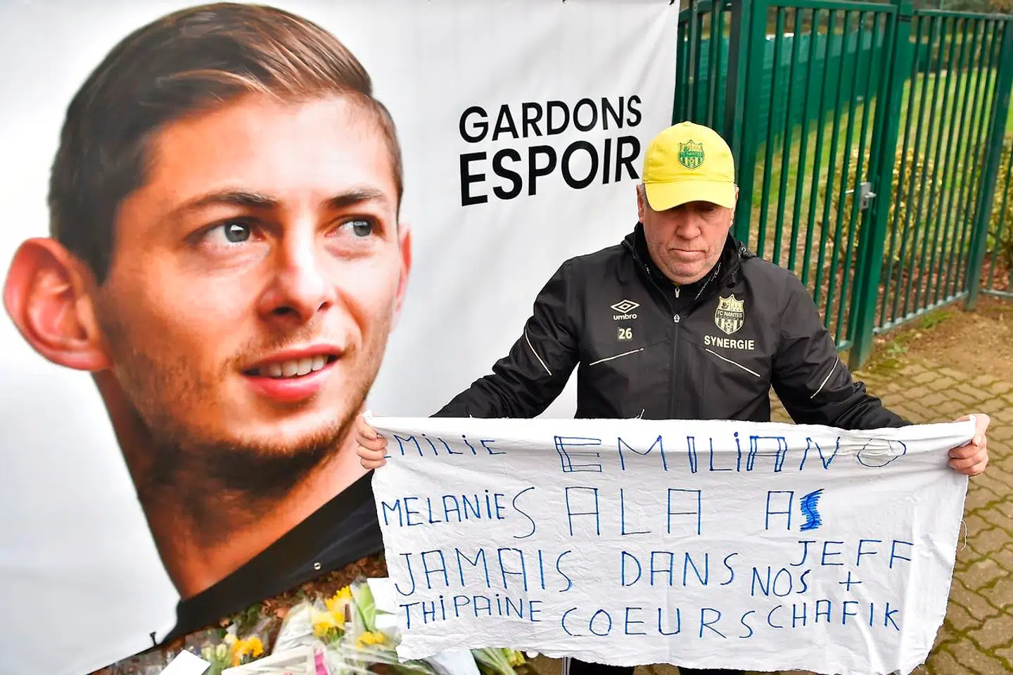 A Nantes supporters holds a banner beside a portrait of Argentinian forward Emiliano Sala prior to a team training session at the FC Nantes training centre La Joneliere in La Chapelle-sur-Erdre, western France, on January 24, 2019, three days after the plane carrying Sala vanished over the English Channel. - Police on January 24 ended their search for new Premier League player Emiliano Sala, saying the chances of finding the Argentine alive three days after his plane went missing over the Channel were "extremely remote". Sala, 28, was on his way from Nantes in western France to the Welsh capital to train with his new teammates for the first time after completing a £15 million ($19 million) move to Cardiff City from French side Nantes on January 19. (Photo by LOIC VENANCE / AFP)