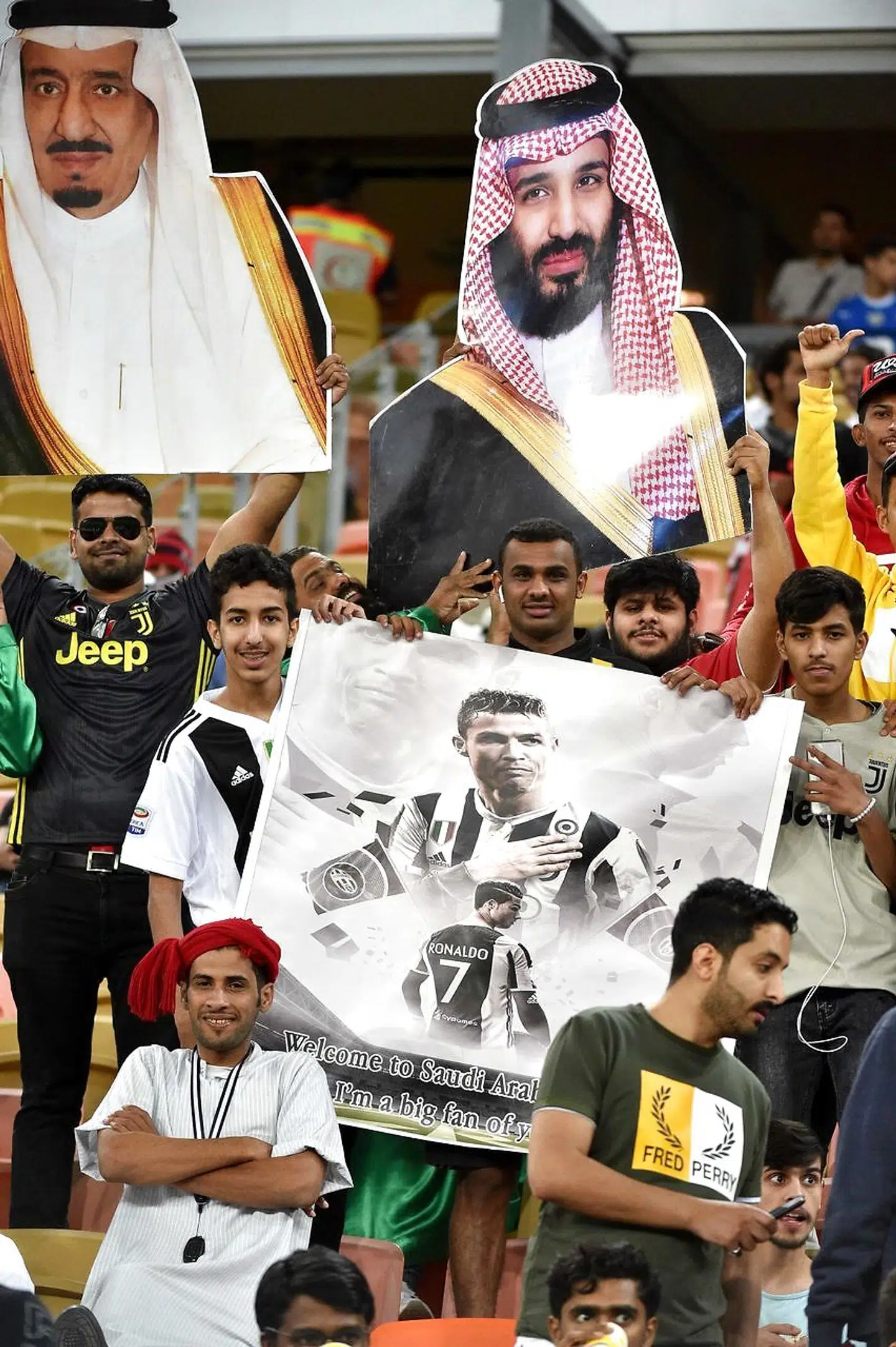 Juventus fans carry a poster of Juventus' Portuguese forward Cristiano Ronaldo and portraits of Saudi King Salman and Crown Prince Mohammad Bin Salman ahead of the Supercoppa Italiana final between Juventus and AC Milan at the King Abdullah Sports City Stadium in Jeddah on January 16, 2019. (Photo by Fayez Nureldine / AFP)