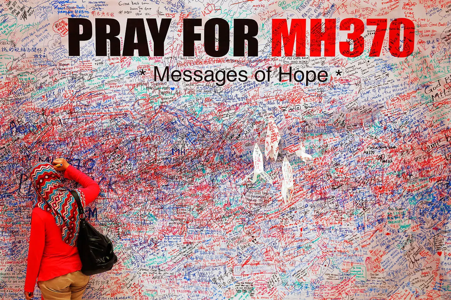 En kvinde skriver en besked om håb for passagererne på MH370 i det centrale Kuala Lumpur.