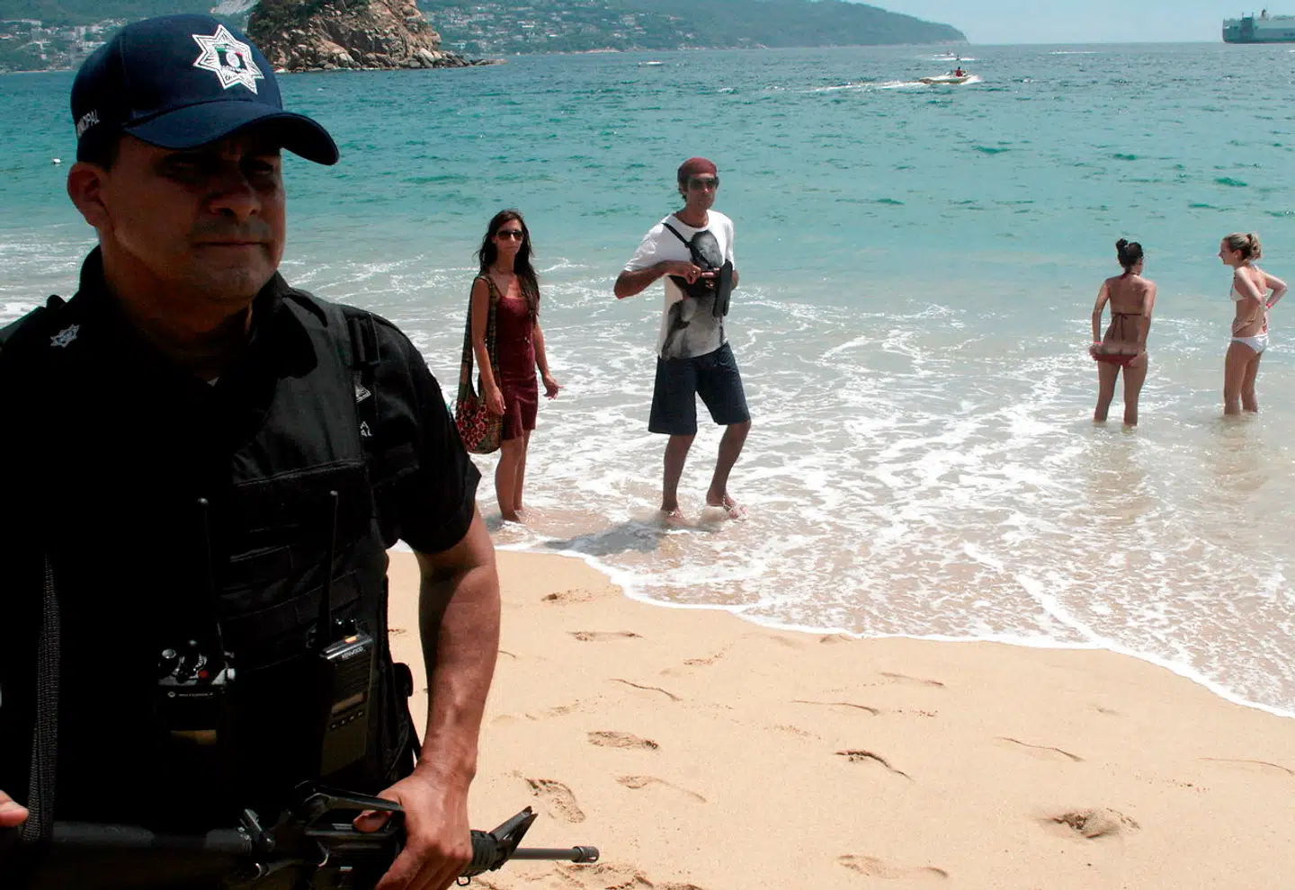 Her ses en sikkerhedsvagt på stranden ved et resort i Acapulcu sammen med turister. Billedet stammer fra 2010 - allerede dengang var turistindustrien bekymret for, at narkoopgør.ville skræmme turister væk.