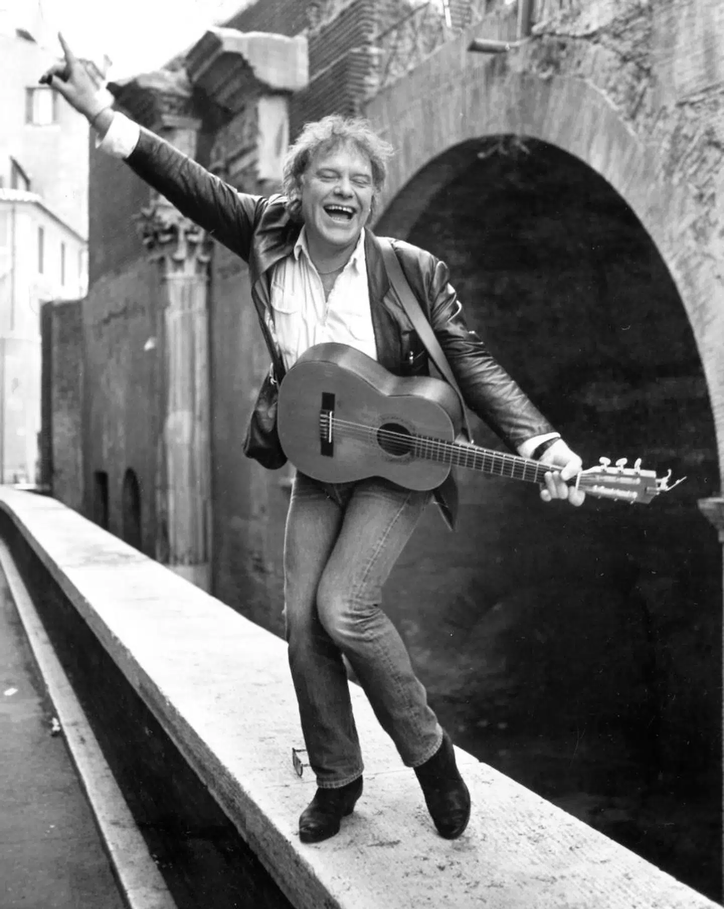 Kim Larsen, sanger, står på kanten af en bro i Rom og spiller guitar og synger.