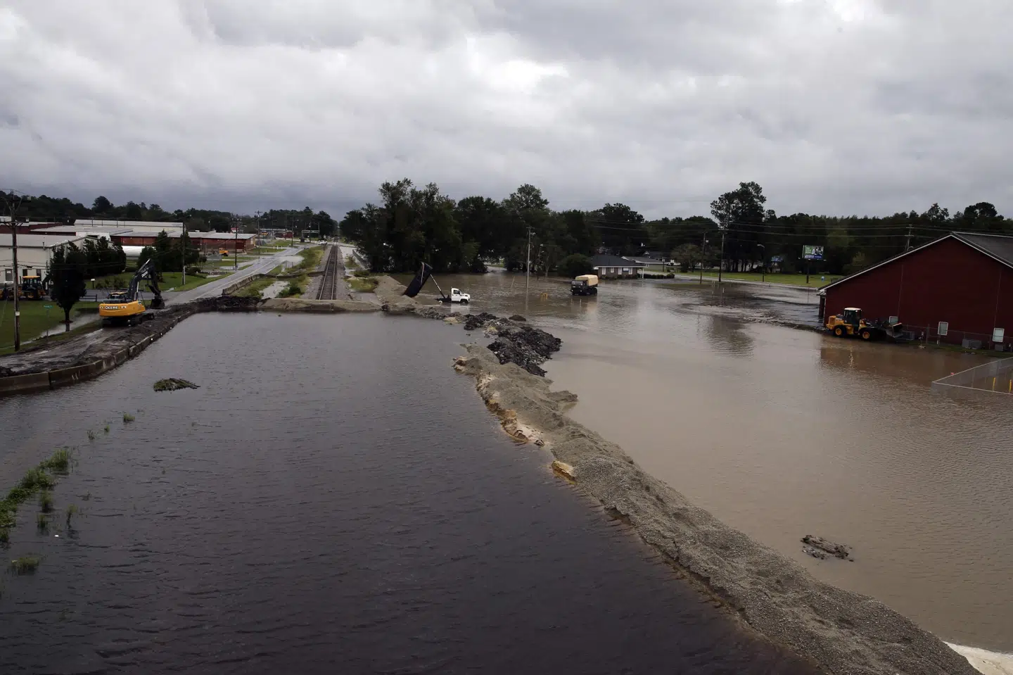 Bulldozere er i færd med at forsøge at bygge en dæmning ved Interstate Highway 95 i Lumberton, North Carolina, søndag. Mange steder her i delstaten og i South Carolina er indbyggere blevet overraskede over, hvor højt vandet er steget på vejene. Alex Edelman/Ritzau Scanpix