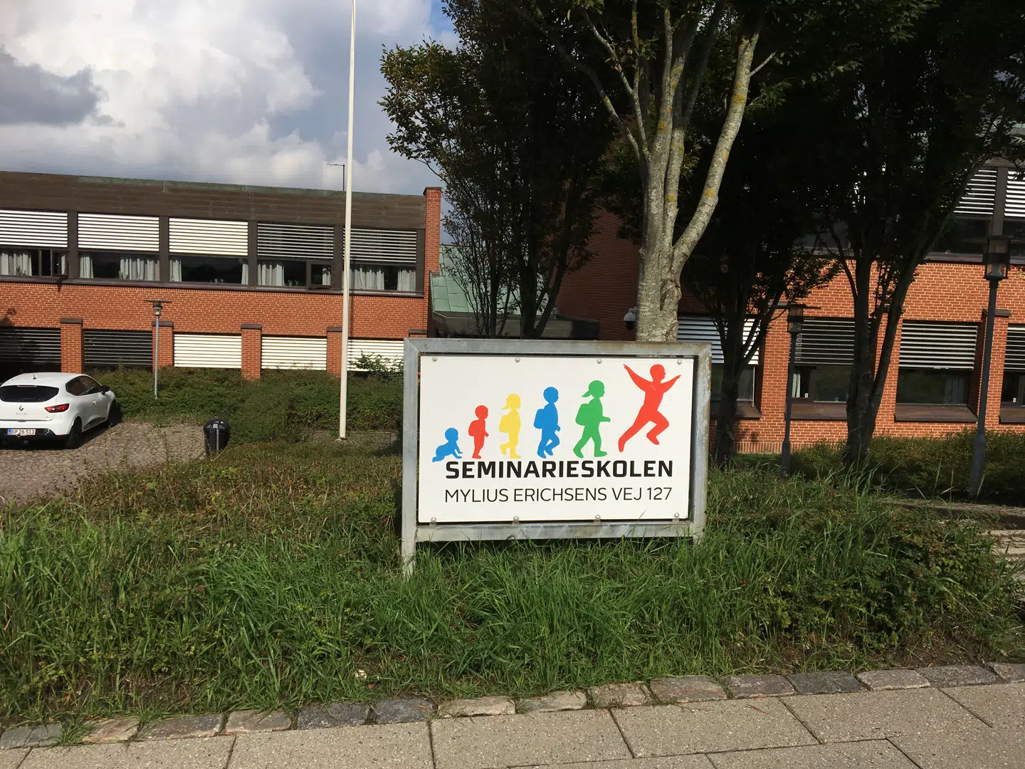 Det er her på Seminarieskolen i Aalborg-bydelen Gug, en kvinde iklædt niqab afleverer sit barn. Dermed overtræder hun tildækningsforbudet. Skolen nægter at have anmeldelsespligt, og Aalborg Kommunes skolerådmand vil heller ikke foretage sig noget. Nu forsøger viceborgmesteren at finde flertal for at tvinge skoleledere og andre ledere i de kommunale institutioner til at indgive anmeldelse ved tilsvarende episoder fremadrettet.Foto: Jens Anton Havskov