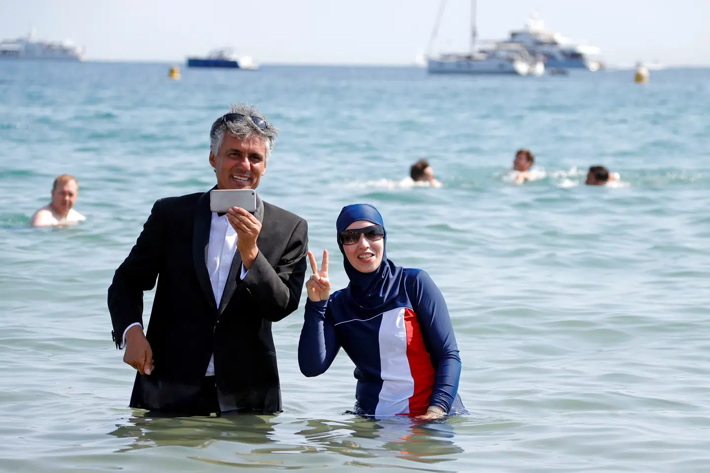 Rigmanden Rachid Nekkaz ses her med en kvinde iført en burkini i Cannes. Han har ifølge ham selv betalt bøder for millioner af kroner for kvinder, som har overtrådt forbud mod at tildække sig. Eric Gaillard/arkiv/Reuters