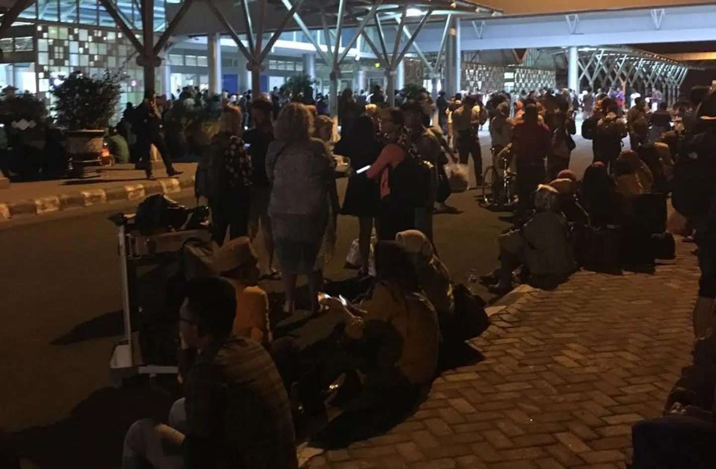 Folk venter ude foran lufthavnen, indtil personalet lader dem komme ind igen efter jordskælvet.