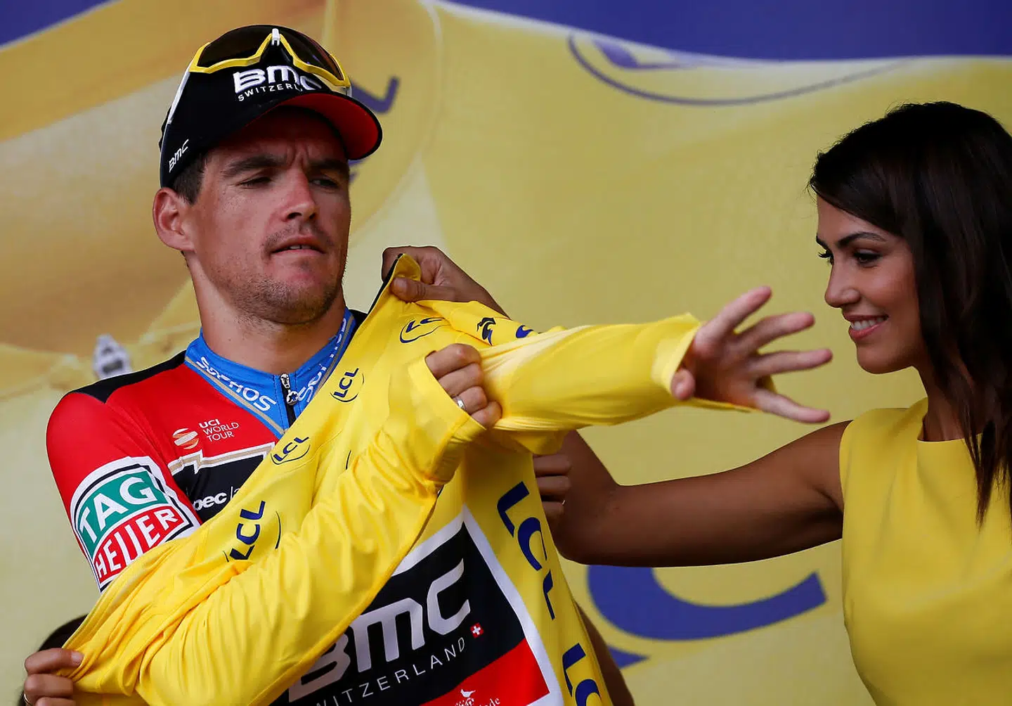 Laurence Galon (th) hjælper Greg van Avermaet med at få den gule trøje på.