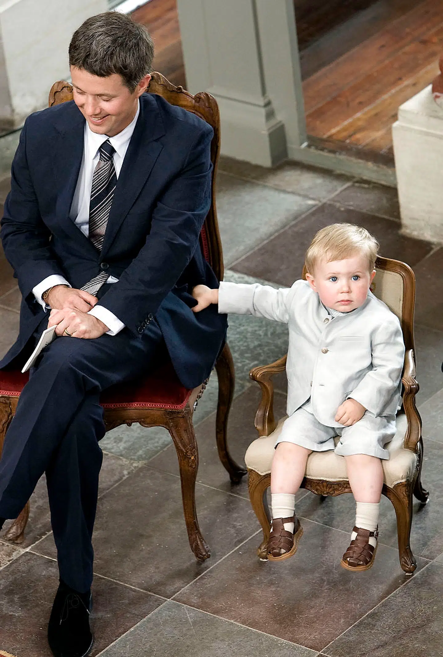 Kronprins Frederik blev ofte set bære rundt på lille prins Christian. Her holder den lille prins godt fast i sin fars jakke under sin søster Isabellas barnedåb.
