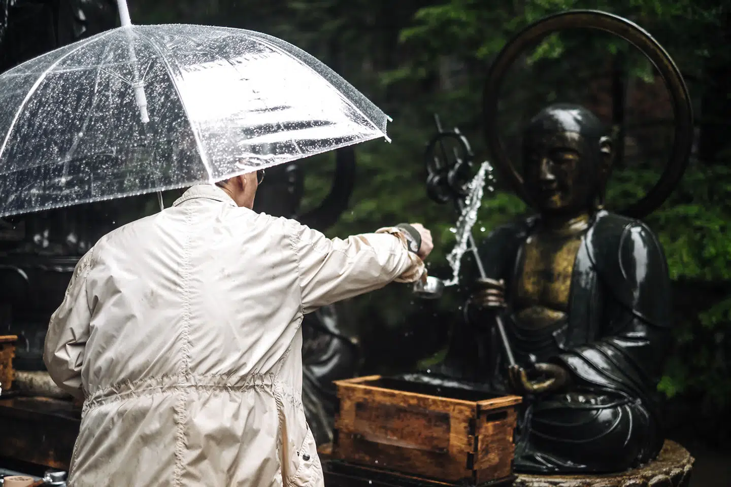 En tilbeder kaster vand på statuen i Mount Koya.