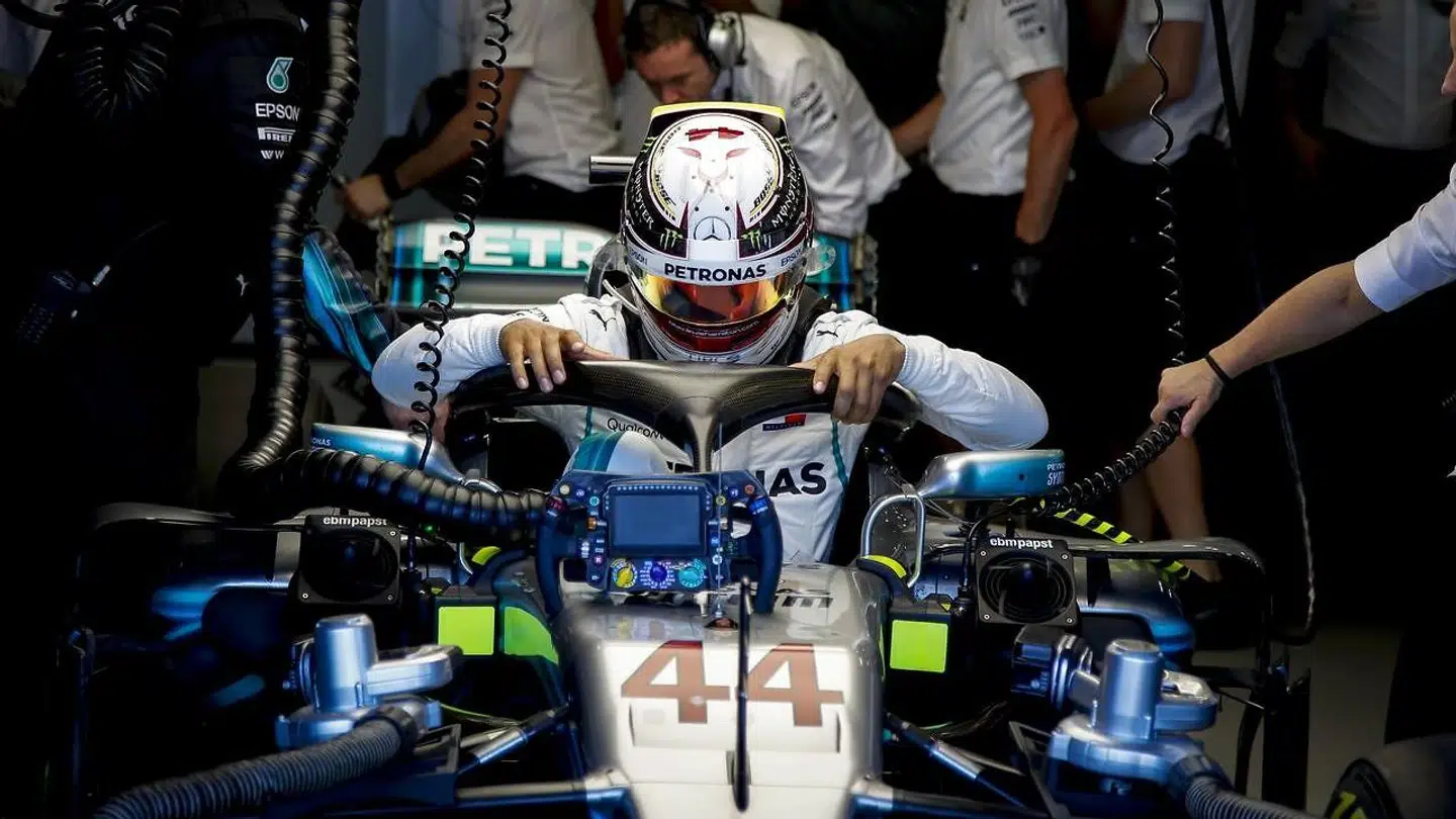 Lewis Hamilton er ikke tilfreds med den nye 'Halo', som han her har fat i, mens han sætter sig ned i sin Mercedes-racer.