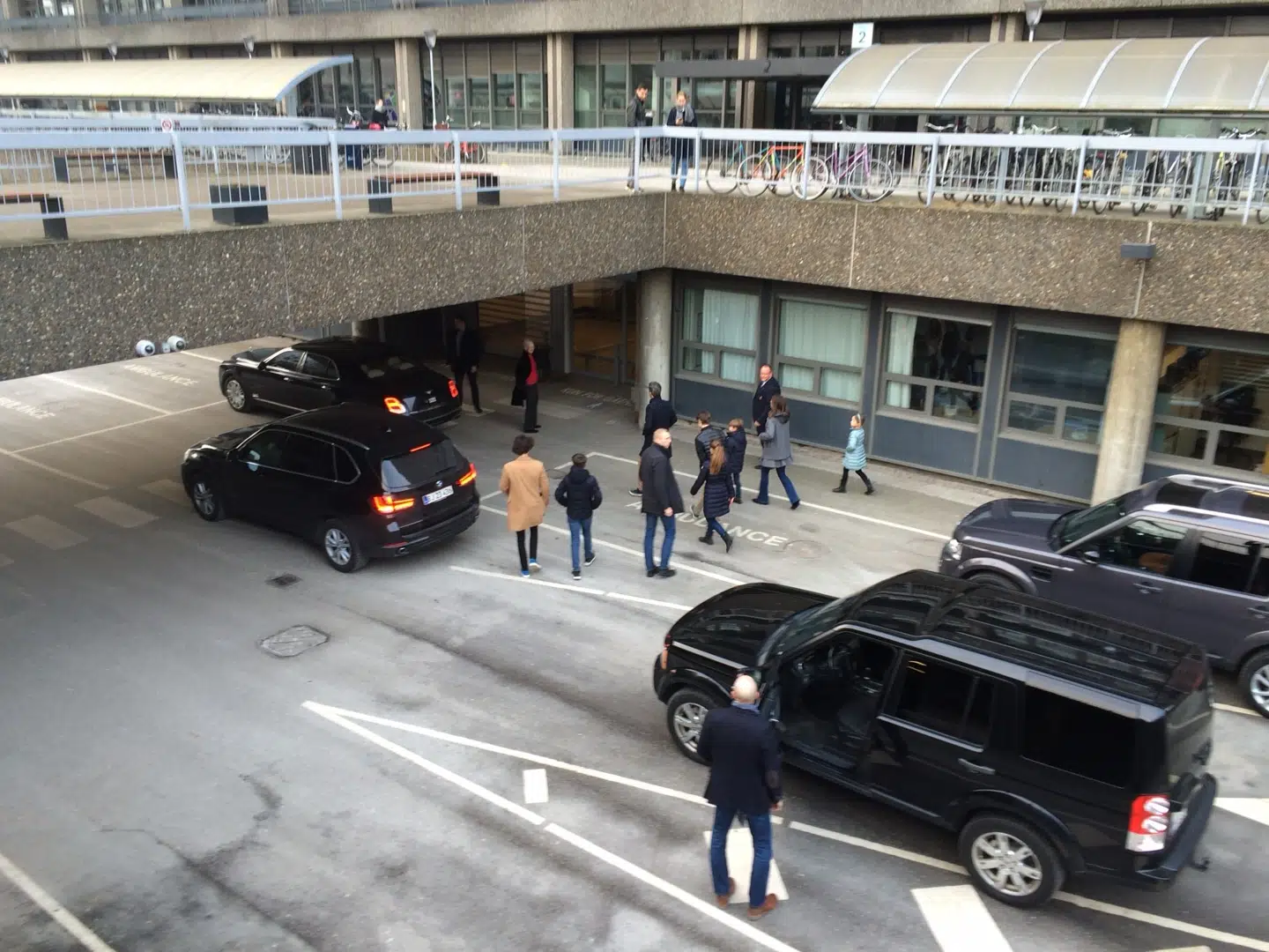 Dronning Margrethe i sort frakke og rød trøje under afventer resten af kongefamilien.