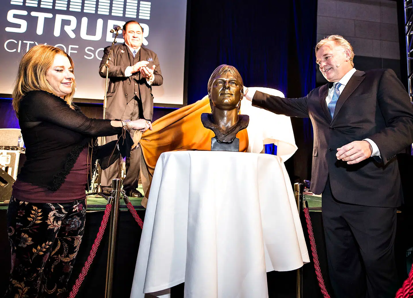 Med i Struer havde Morten Andersen også sin kone Jennifer, der her er med til at afsløre bronzebusten, som ellers normalt står i Pro Football Hall of Fame i Canton, Ohio. Til stede var også blandt andre hans forældre, Hanne og Erik, samt flere venner fra opvæksten i Struer, mens sønnerne Sebastian og Aiden var blevet hjemme i Atlanta. . Foto: Henning Bagger