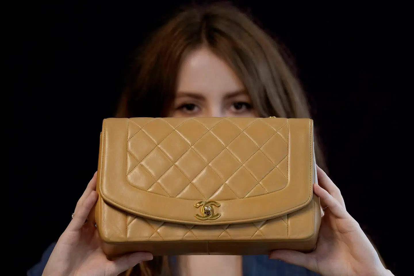 A Bonhams employee displays a beige lambskin medium Chanel 'Diana' bag (1991 - 94) in London, Wednesday, Oct. 6, 2021. The Diana single flap bag was produced for only a few years in the early 1990s. Princess Diana popularised the piece, which she carried so frequently that designer Karl Lagerfeld renamed the handbag in her honour. The bag estimated at 2, 000-3, 000 UK Pounds ( 2, 700-4, 000 US Dollars) will be up for auction at Bonhams in London on Oct.12 in the designer handbags and fashion sale. (AP Photo/Kirsty Wigglesworth)