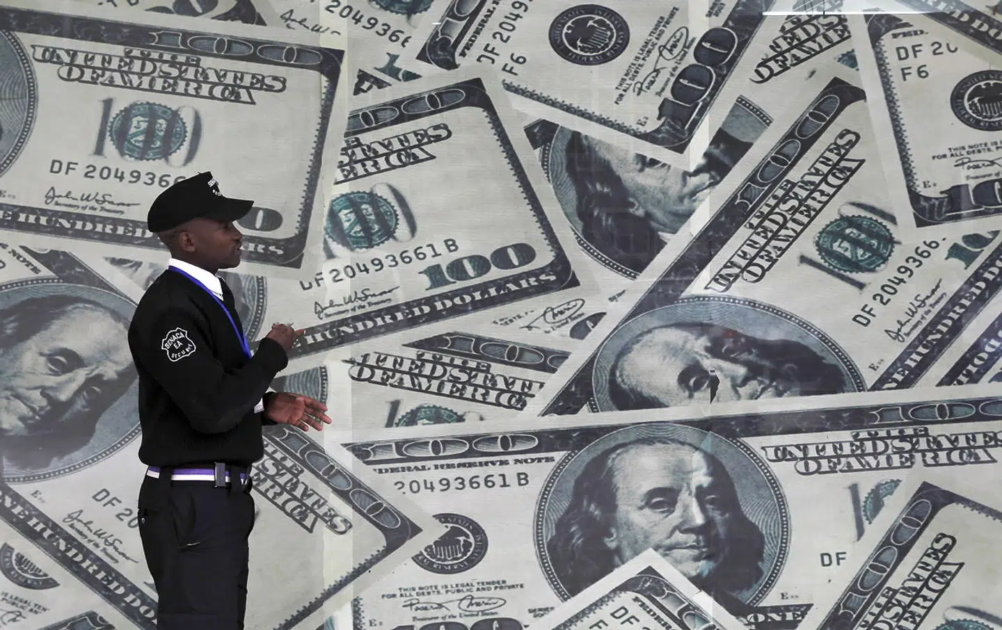 A security guard walks past a montage of U.S. dollar bills outside a currency exchange bureau, ahead of a scheduled state visit by U.S. President Barack Obama, in Kenya's capital Nairobi July 23, 2015. Obama will land in Kenya on Friday with a mission to strengthen U.S. security and economic ties, but his personal connection to his father's birthplace will dominate a trip that Kenyans view as a native son returning home. REUTERS/Thomas Mukoya TPX IMAGES OF THE DAY