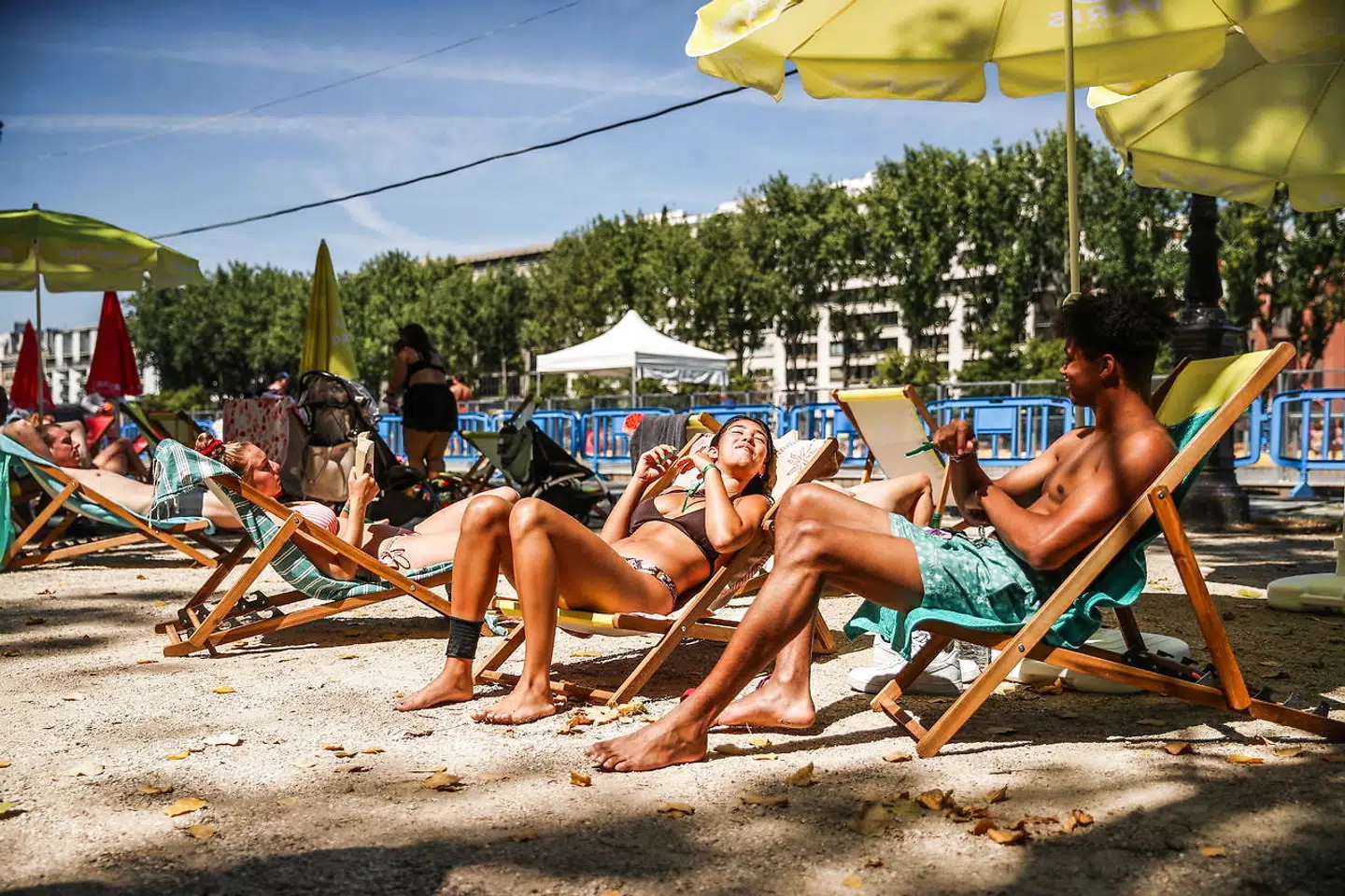 epaselect epa08553557 People sit on beach chairs in the sun next to a swimming pool inside Paris Plages at the canal basin of the Bassin de la Villette, in Paris, France, 18 July 2020. Paris Mayor Hidalgo launched the annual outdoor summer event Paris Plages on 18 July 2020. The temporary artificial beaches will run until 31 August 2020, with extra health precautions and instructions in place due to the ongoing pandemic of the COVID-19 disease caused by the SARS-CoV-2 coronavirus. EPA/MOHAMMED BADRA