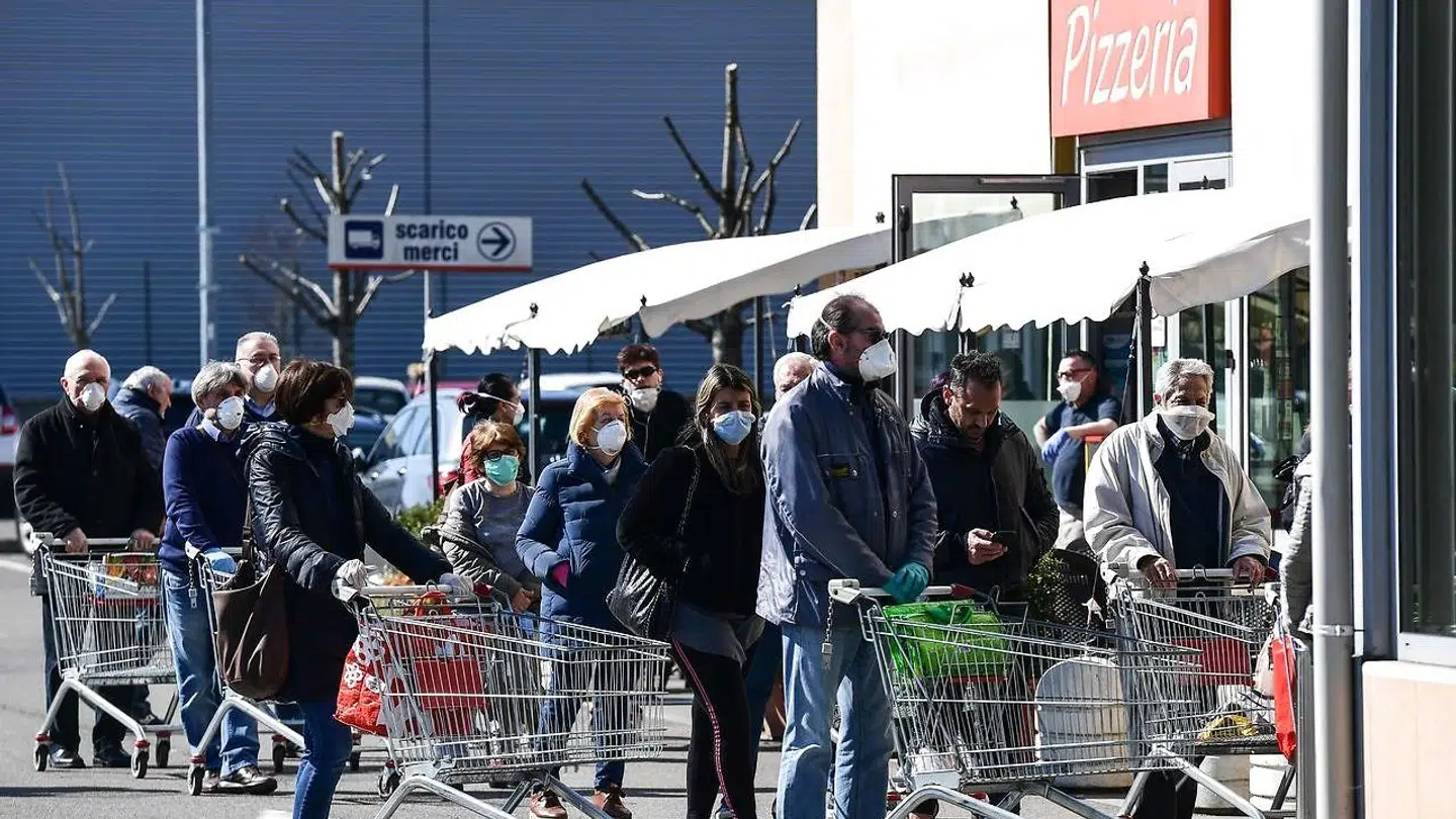 Her venter indbyggere i Milano med masker på at kunne komme ind at handle. Italiens 60 millioner indbyggere har fået indført en lang række restriktioner for at begrænse udbredelsen af COVID-19. Frem til 13. marts har mindst 1000 italienere ministet livet på grund af virussen.