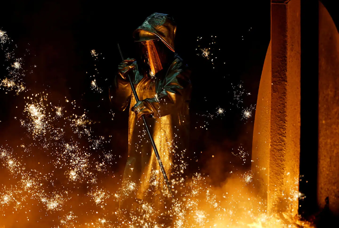 FILE PHOTO: A steel worker stands amid sparks of raw iron coming from a blast furnace at a ThyssenKrupp steel factory in Duisburg, Germany, November 19, 2019. REUTERS/Leon Kuegeler/File Photo