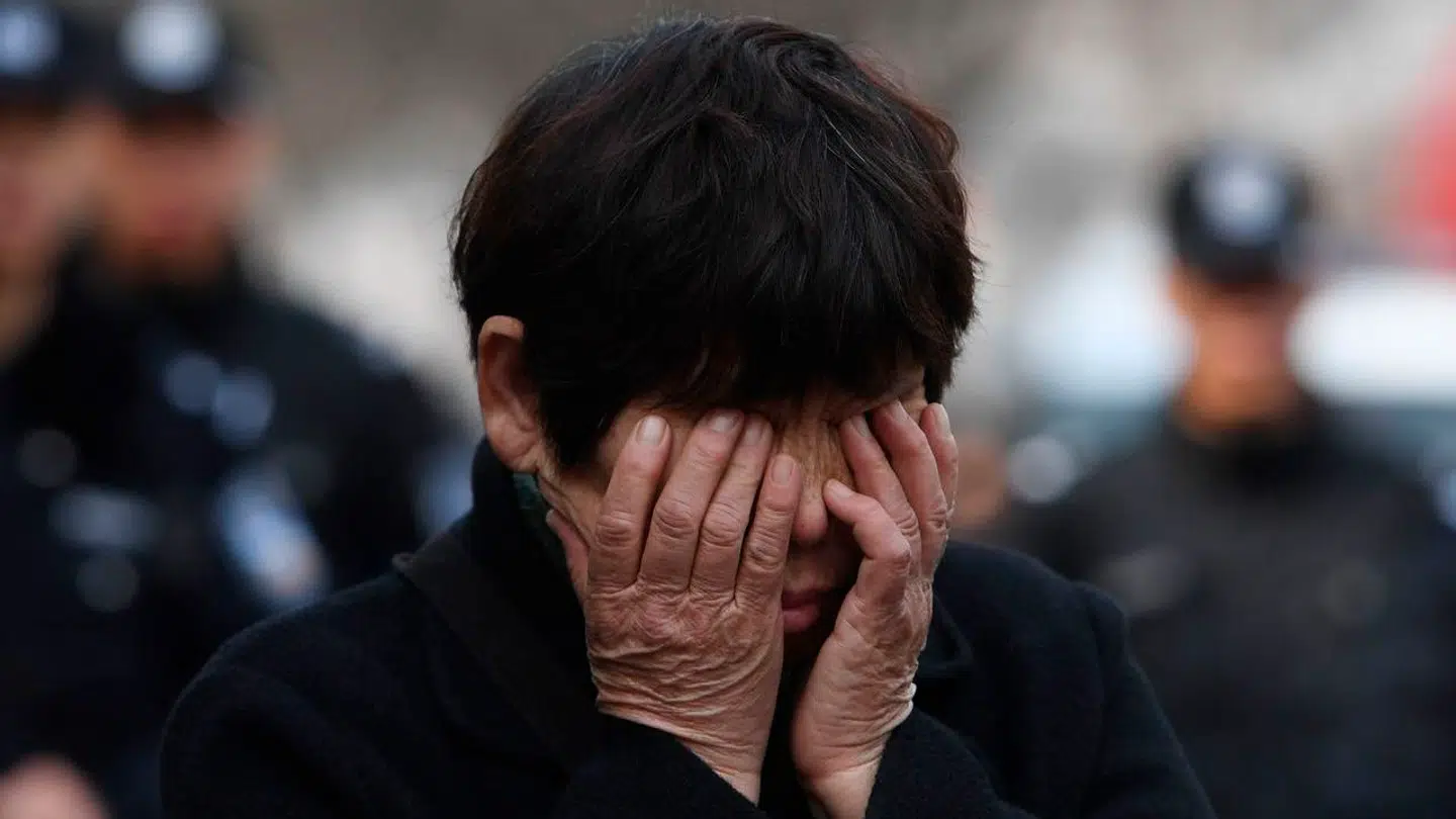 En pårørende til en af de savnede personer på Malaysia Airlines-flyet MH370 græder foran Kinas udenrigsministerium i Beijing (arkivfoto). Nu har en komiker skabt en mindre diplomatisk krise mellem Malaysia og Singapore med en joke om det forsvundne fly.