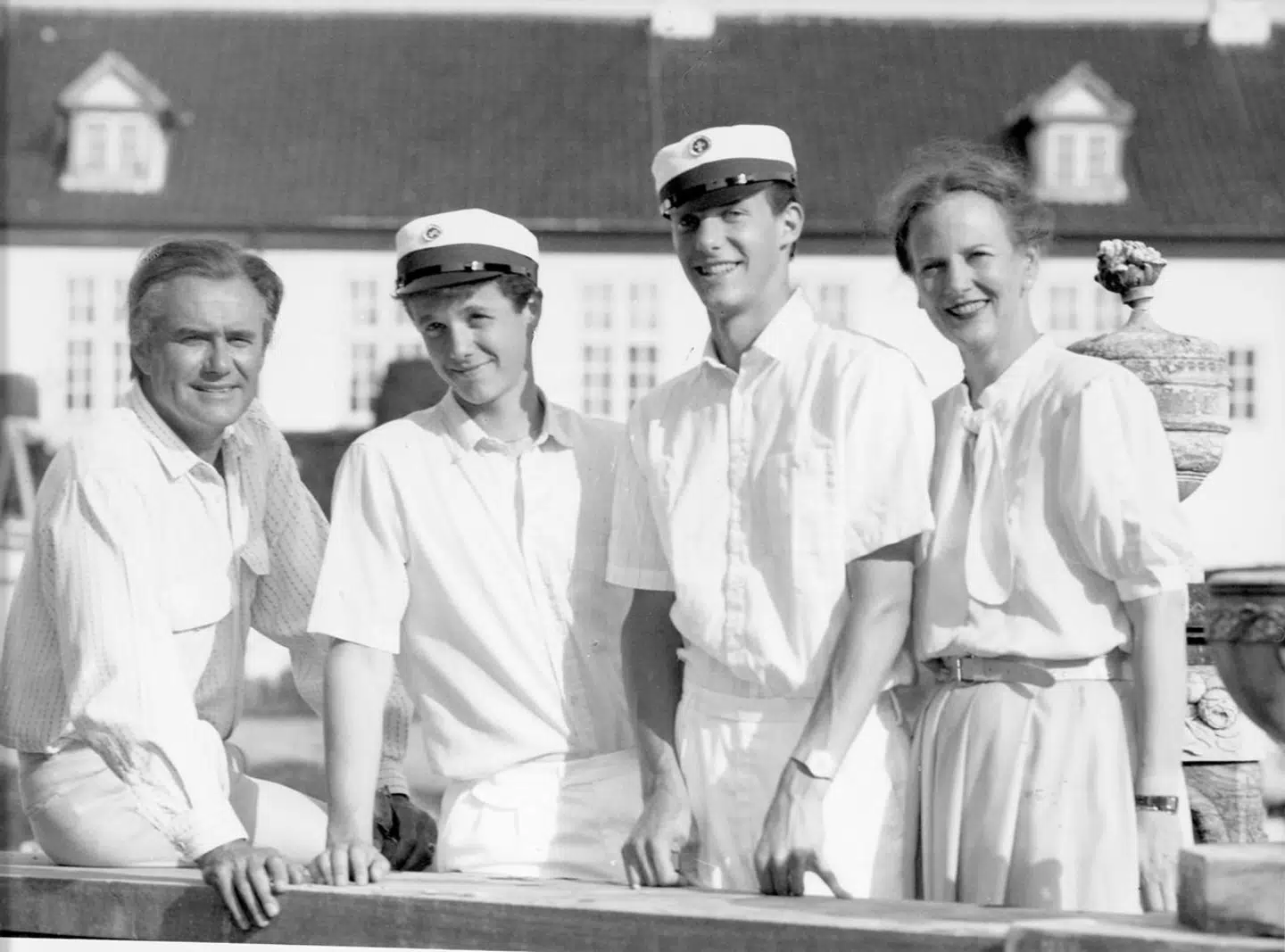 Her ses kronprins Frederik og prins Joachim med studenterhuer omgivet af deres far og mor. Begge har studenterhuer på fra C.L. Seifert.