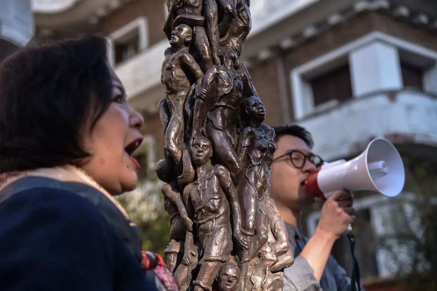Den fremtrædende aktivist og partiformand Nathan Law er en af de otte personer, som politiet i Hongkong nu udlover en dusør for. Her ses han med en megafon under en demonstration uden for Kinas ambassade i Rom i oktober 2021. Ved siden af ham står en kopi af den danske kunstner Jens Galschiøts skulptur Skammens Søjler, der er lavet til minde om ofrene på Den Himmelske Freds Plads i Beijing i 1989. Andreas Solaro/Ritzau Scanpix