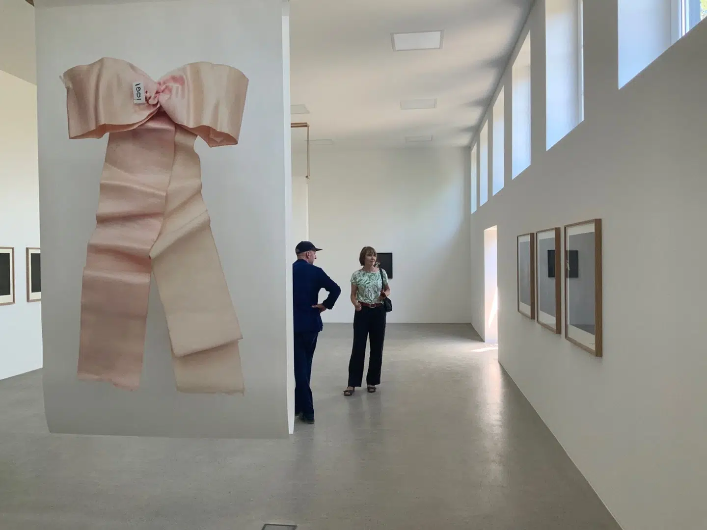 Tobias Posselt (t.v.) ved et af Trine Søndergaards store sløjfefotos, der fungerer fint i det højloftede rum. Hele udstillingen er en lavmælt, men rig oplevelse.