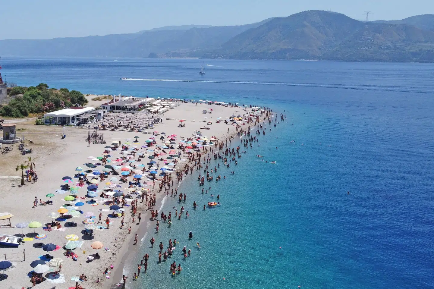 Mens det på strande som denne i Italien næsten kan blive for varmt til at bade, må danskerne finde regntøjet frem i den kommende uge. Giovanni Isolino/Ritzau Scanpix