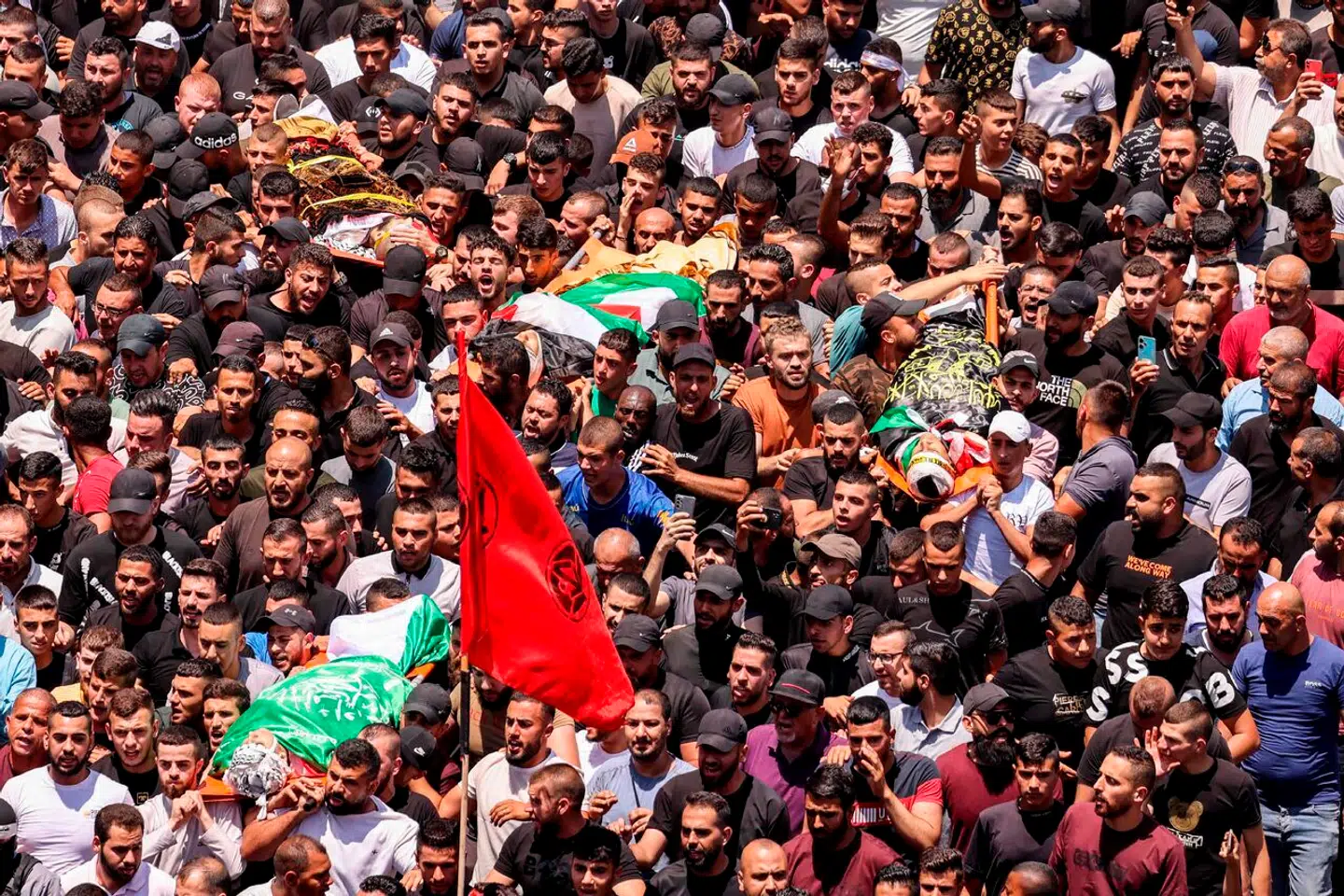 EDITORS NOTE: Graphic content / TOPSHOT - Mourners carry the bodies of Palestinians killed in clashes the previous day in the Israeli military operation during the funeral in Jenin in the occupied West Bank on July 5, 2023. The Israeli military launched the raid on the Jenin refugee camp early on July 3, during which 12 Palestinians and one Israeli soldier were killed. (Photo by Jaafar ASHTIYEH / AFP)