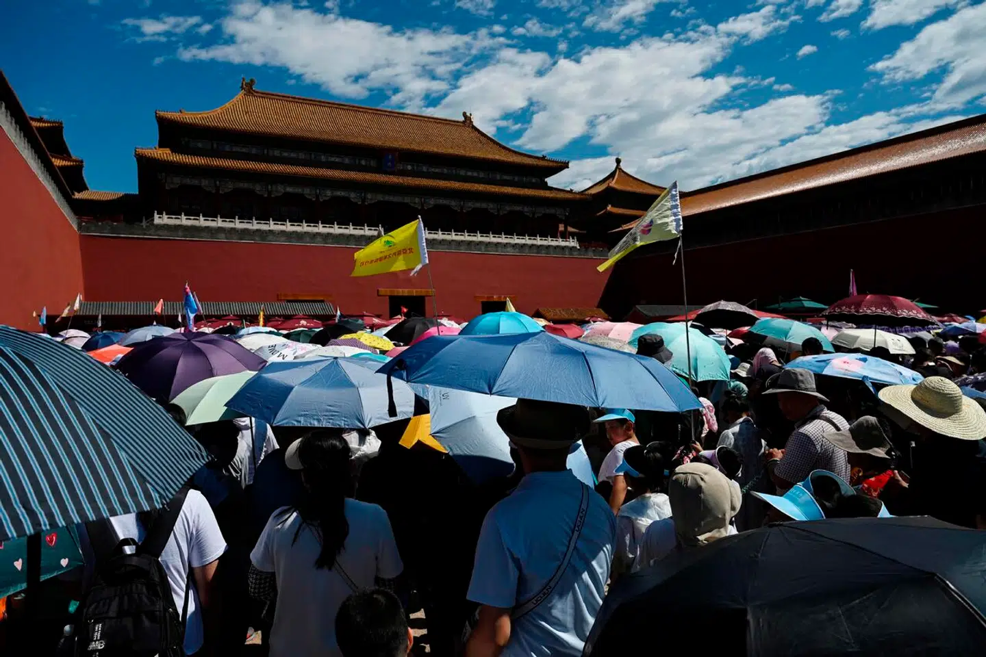 Her ses en række besøgende til den forbudte skov i Beijing i dag den 9. juli, hvor temperaturerne stadig er så høje, at folk må bære hatte og medbringe paraplyer for at undgå solstik.