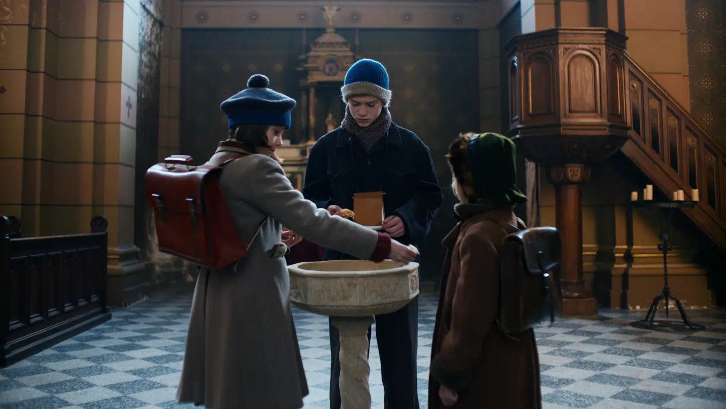 Ella Josephine Lund Nilsson, Bertram Bisgaard og Ester Birch Beck, der spiller filmens tre centrale børnekarakterer, beskytter sig forgæves med vievand i Den Franske Skoles kapel forud for den store katastrofe. Foto: Lasse Frank