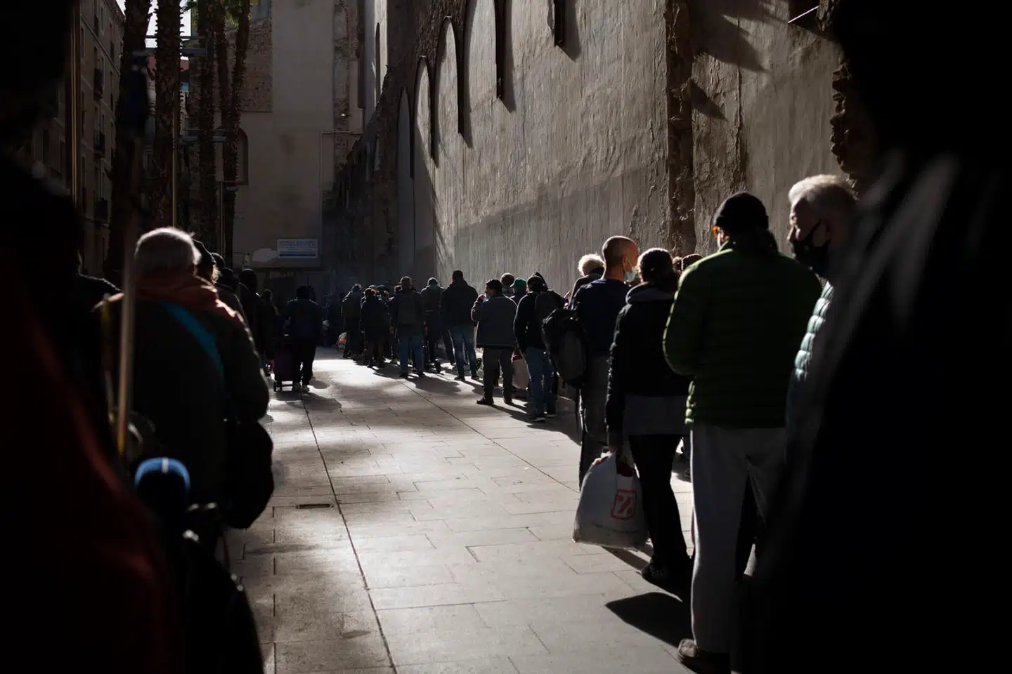 Hjemløse og andre fattige står i kø for at få mad uden for en kirke i Barcelona. Når relativt få spanierne blev tvunget til at gå fra hus og hjem under pandemien, var det, fordi aftaler mellem regeringen og arbejdsgiverne sikrede deres job.