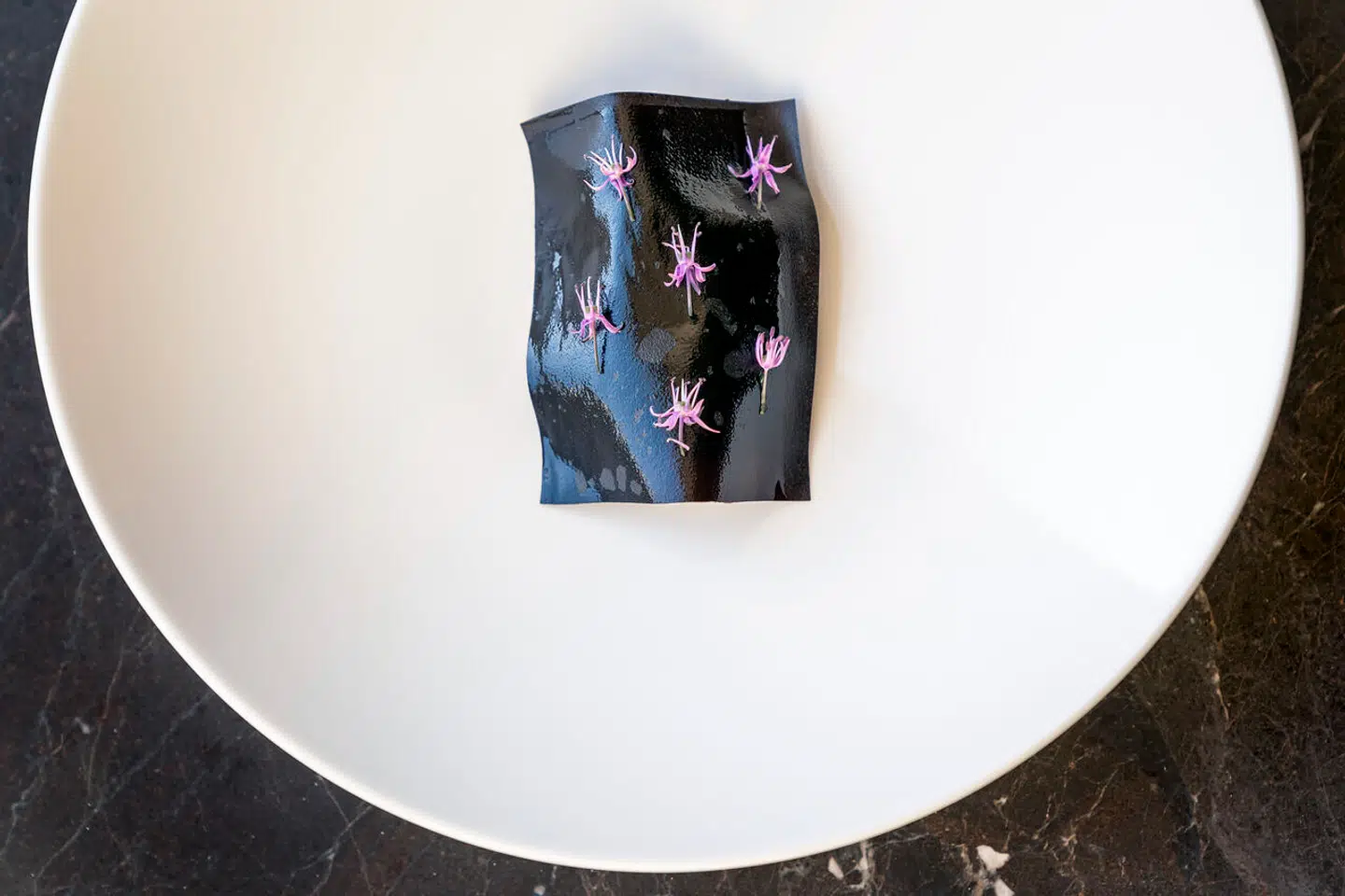 En ret så smuk, at den kunne have været serveret på Noma eller Geranium: Hamachi gemt under maltlæder med løgblomster.