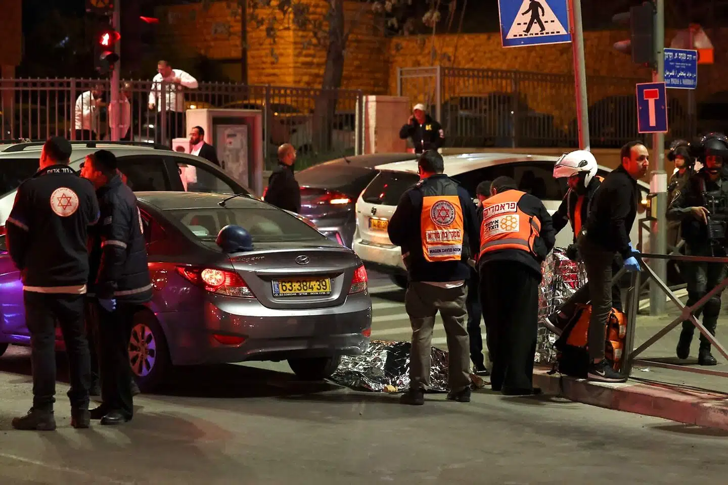 Israelske ambulancefolk og politifolk står ved siden af en indhyllet formentlig død person, efter en gerningsmand har åbnet ild mod folk, der har forladt en synagoge i Jerusalem. – Foto: Ahmad Gharabli/Ritzau Scanpix
