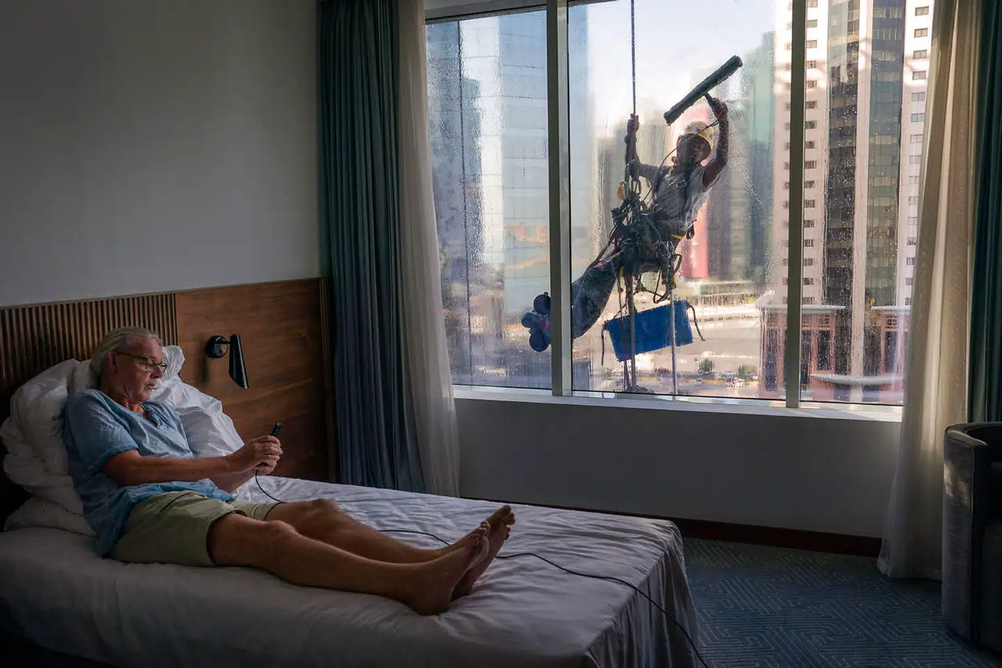 En vinduespudser er i gang med at vaske vinduet på 9. sal til Berlingskes hotellejlighed i Doha.