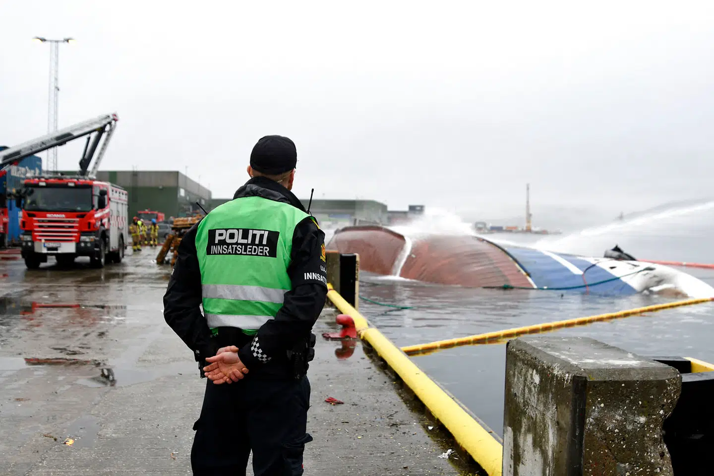 En brasiliansk statsborger blev mandag eftermiddag pågrebet af norsk politi på vej til arbejde på universitetet i den norske by Tromsø. Billedet viser en norsk politibetjent, der kigger på den brændte russiske båd »Bukhta Naezdnik«, der sank i Tromsø havn. Rune Stoltz Bertinussen / NTB Scanpix / AFP