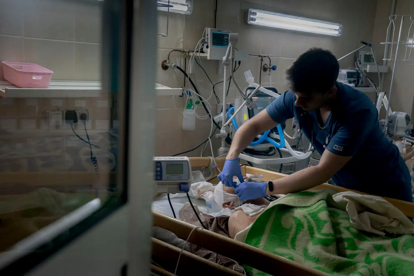 En kirurg retter på en lungemaskine, der er koblet på en såret soldat. Den sårede deler stuen med tre andre. Krigen har fyldt det lille sygehus i det sydlige Ukraine til bristepunktet.