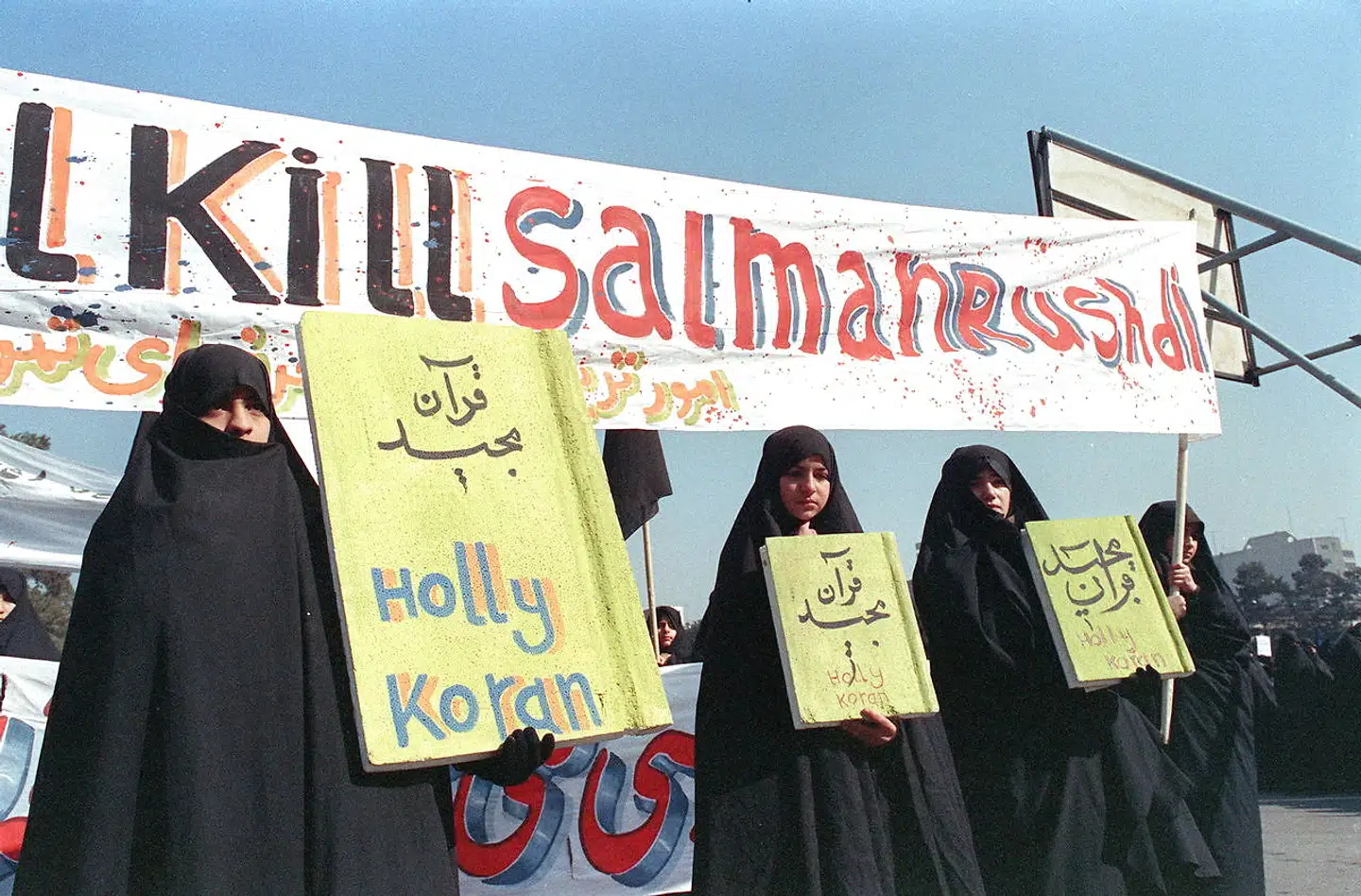 Efter at Salman Rushdie i 1988 udgav romanen »De sataniske vers« blev der udstedt en fatwa – et muslimsk funderet dekret – på baggrund af bogens islamkritik. Her ses iranske kvinder i 1989 holde et banner med skriften »dræb Salman Rushdie«.
