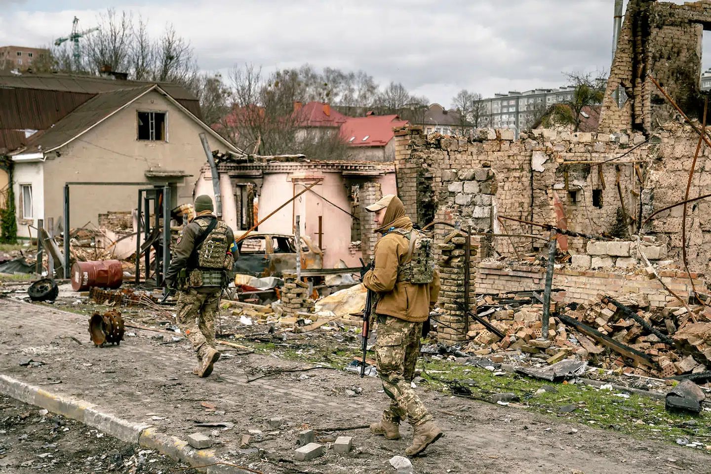 To ukrainske soldater går gennem en sønderbombet gade i Butja.