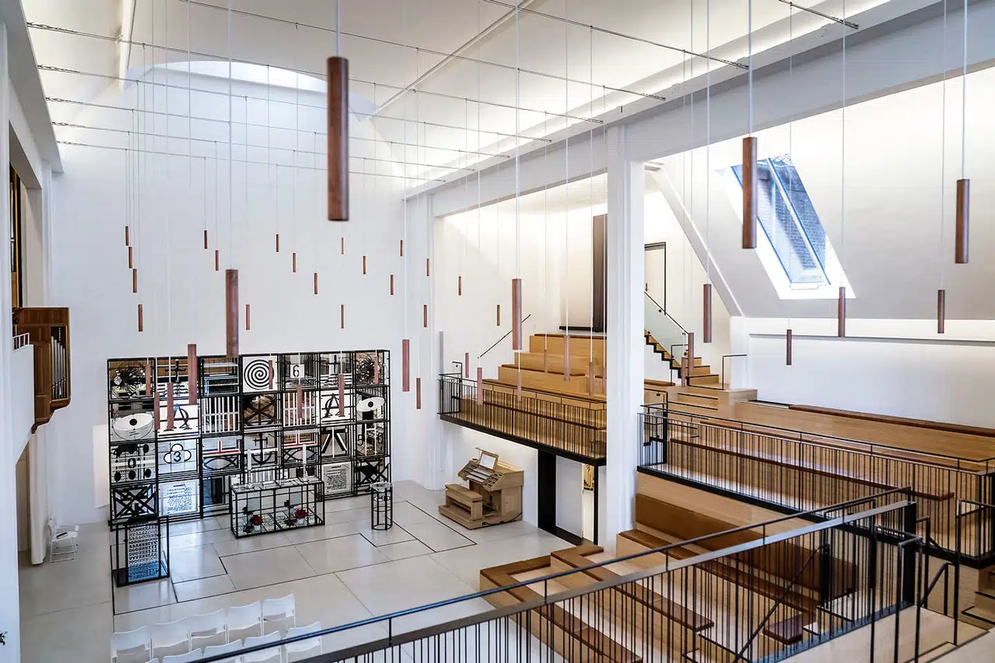 Det asymmetrisk disponerede rum, den legesyge altertavle og lampernes bølgebevægelse spiller sammen og danner tilsammen en musikalsk og sjælden rumoplevelse.