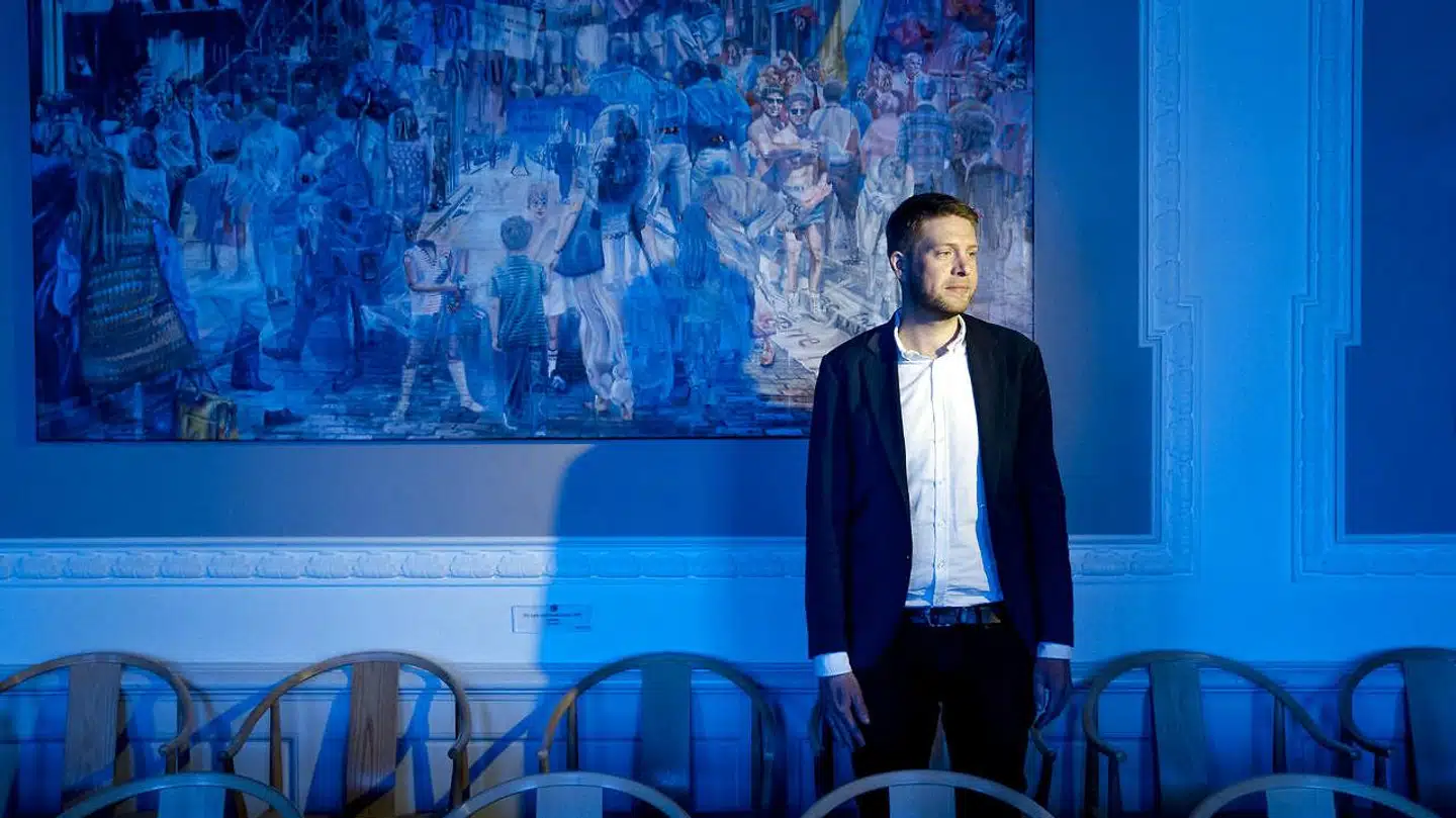 Kulturordfører for Socialdemokratiet, Kasper Sand Kjær, fotograferet ved Jacob Brostrups maleri i Socialdemokratiets gruppeværelse. Maleriet viser den optimistiske stemning i 1990erne efter kommunismens fald. Man ser koryfæer som John F. Kennedy, Willy Brandt og danske socialdemokrater som Poul Nyrup Rasmussen, Svend Auken og Mogens Lykketoft. Kasper Sand Kjær siger, at denne fremtidsoptimisme er væk nu.