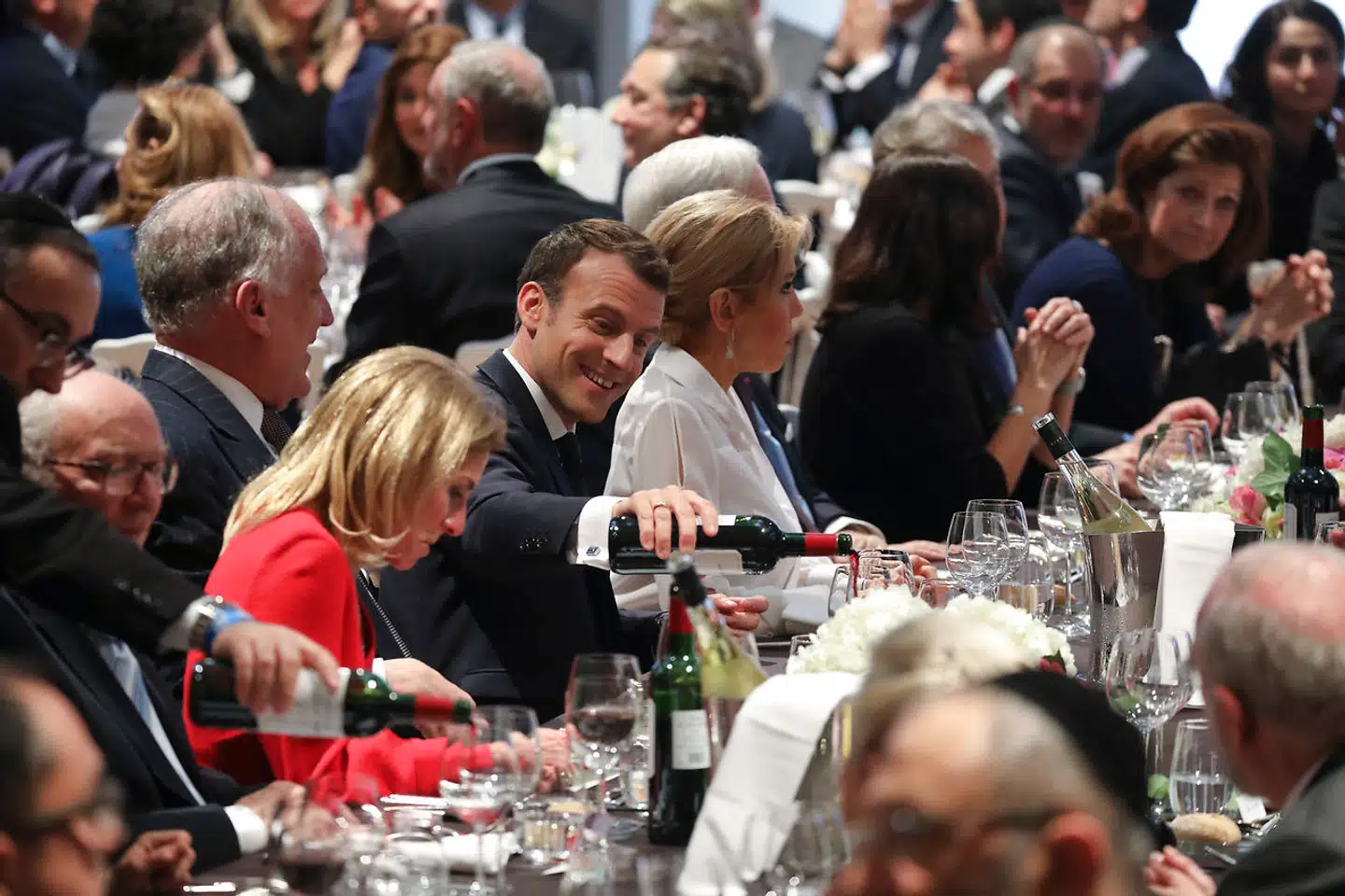 For Emmanuel Macron hænger bordets glæder uløseligt sammen med et godt glas vin. Her skænker den franske præsident op under en middag i Frankrigs jødiske trossamfund.